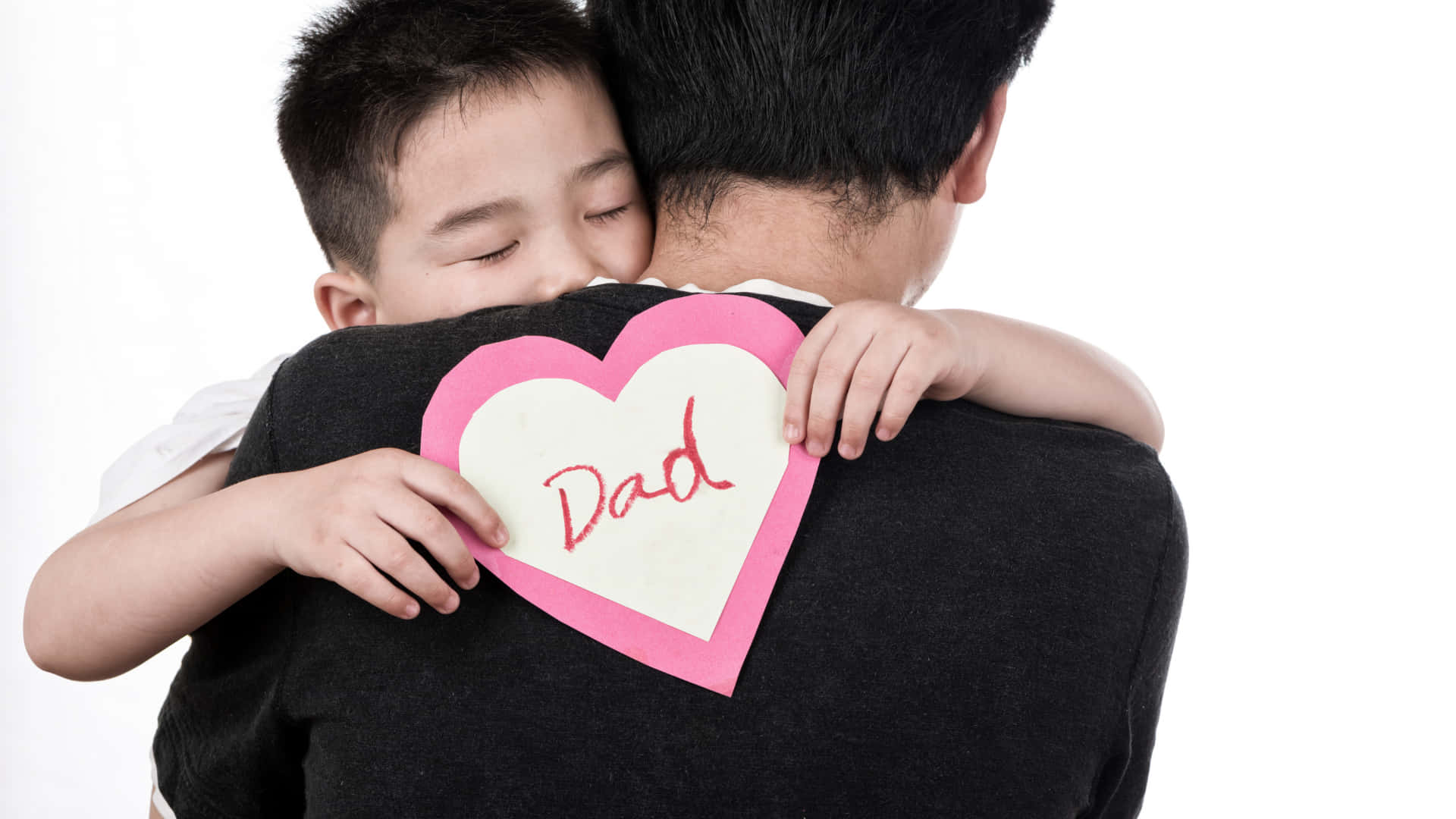 孩子擁抱父親，拿著手作心形寫著爸爸