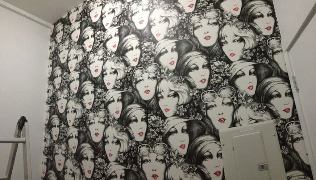Installation Art 桌布 壁紙 — 牆上覆蓋著重複的黑白圖案，圖案為風格化的女性面孔，帶有紅唇和花卉點綴。