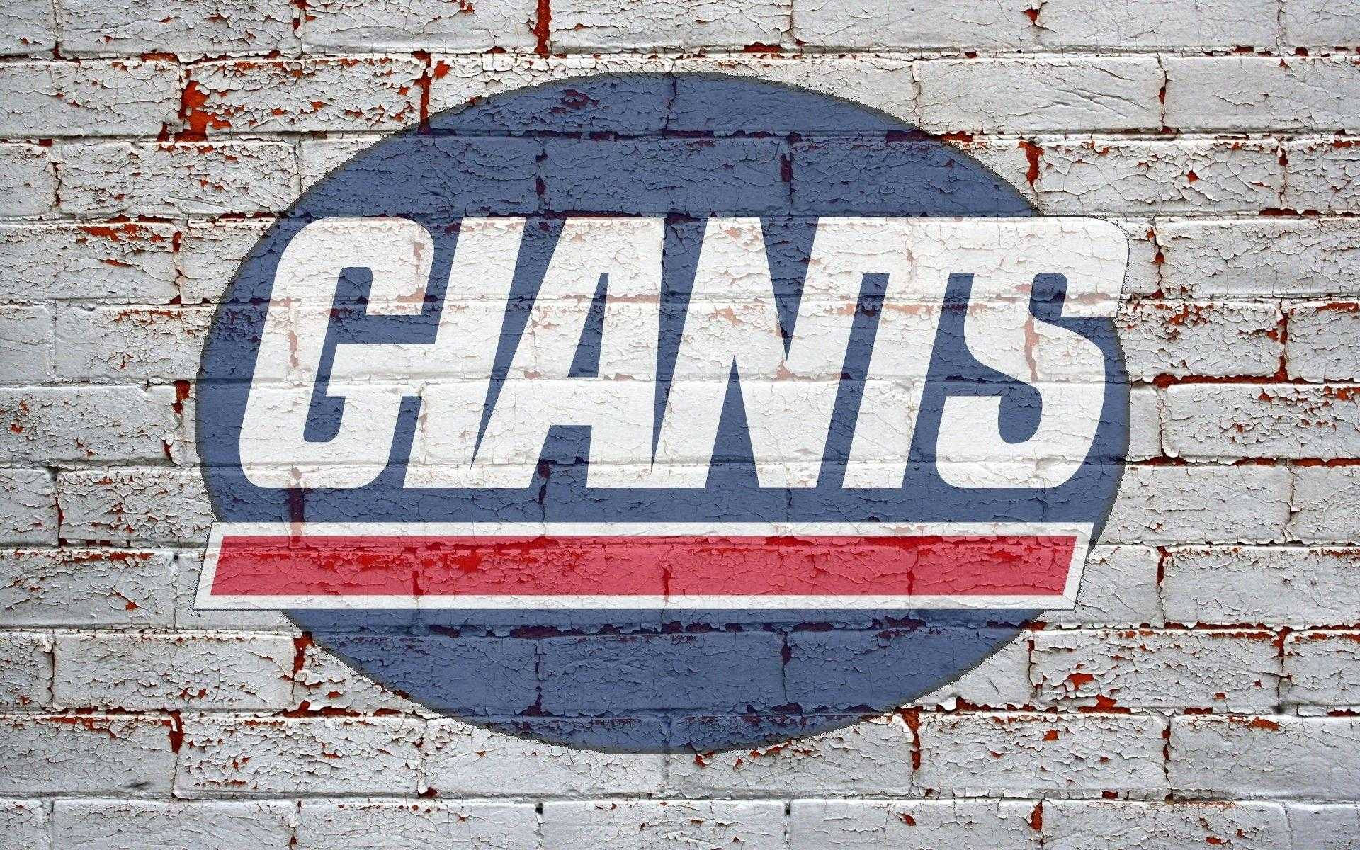 牆面繪製紐約巨人隊徽 壁紙 — 一個風化的「GIANTS」標誌，以粗體白色、紅色和藍色繪製在破裂剝落的白色磚牆上。