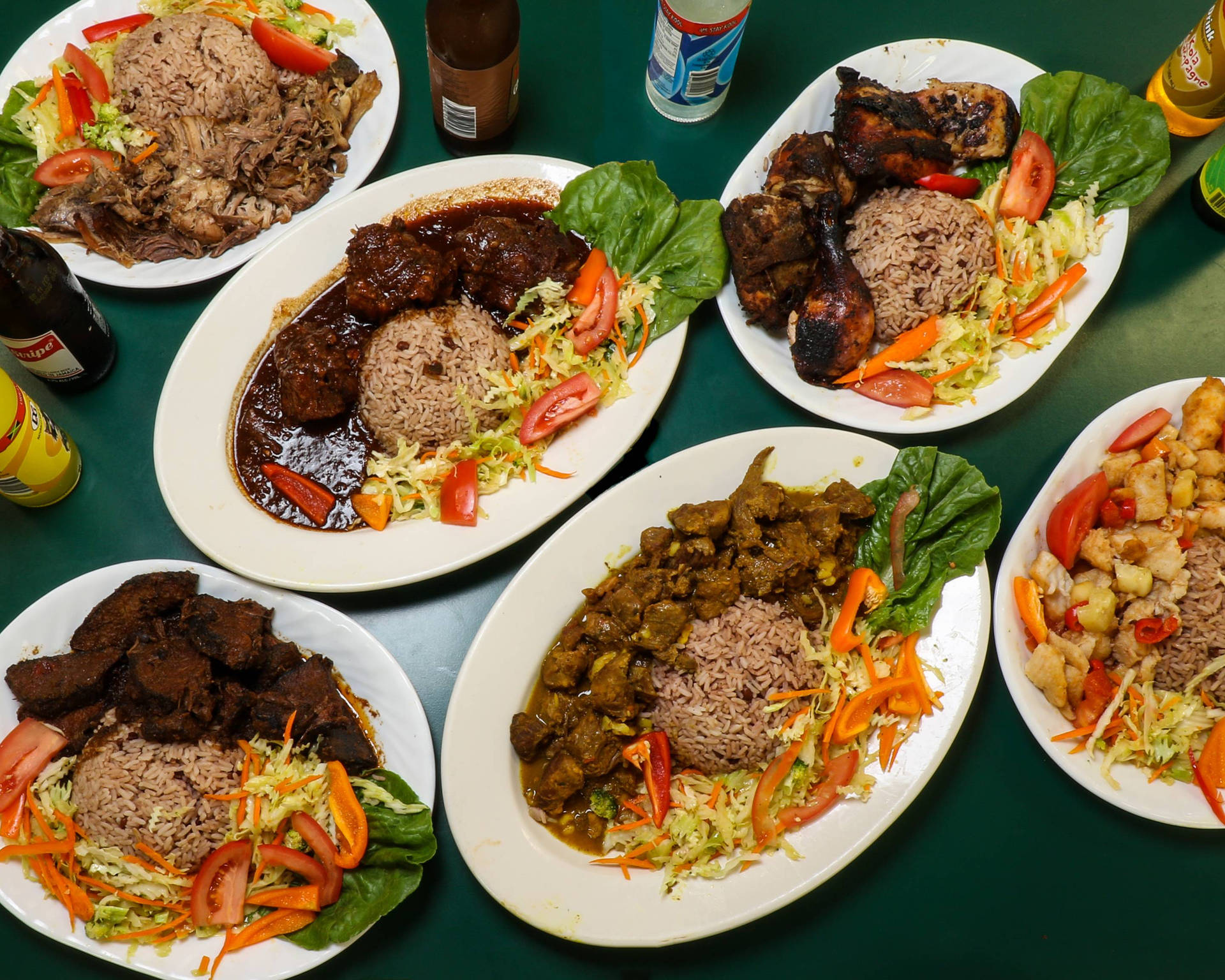 六盤包含肉、米飯和蔬菜的餐點，放在綠色桌子上。