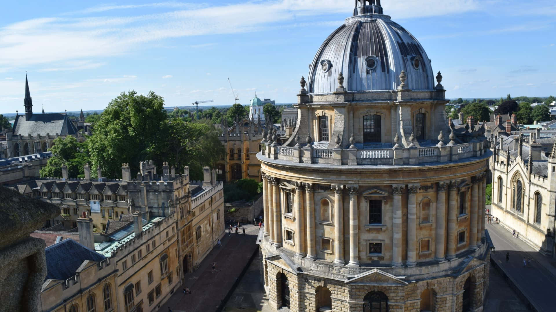 UK 桌布 壁紙 — 牛津拉德克利夫相機圓頂和歷史石建築的鳥瞰圖，天空湛藍，白雲點綴。