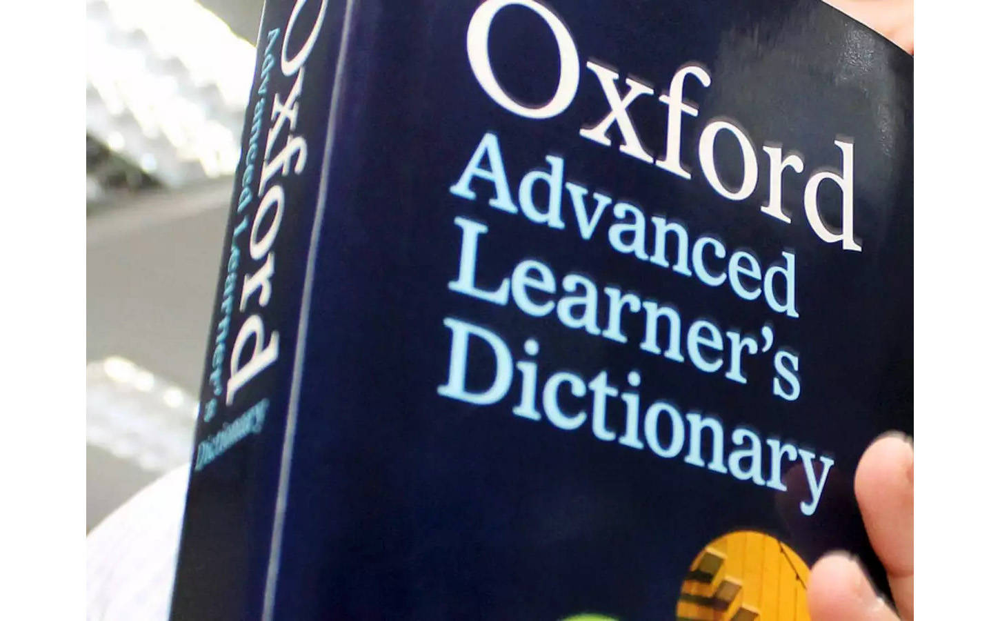 牛津高階詞典 壁紙 — 一隻手拿著深藍色Oxford Advanced Learner's Dictionary的特寫，上面有白色和淺藍色文字。