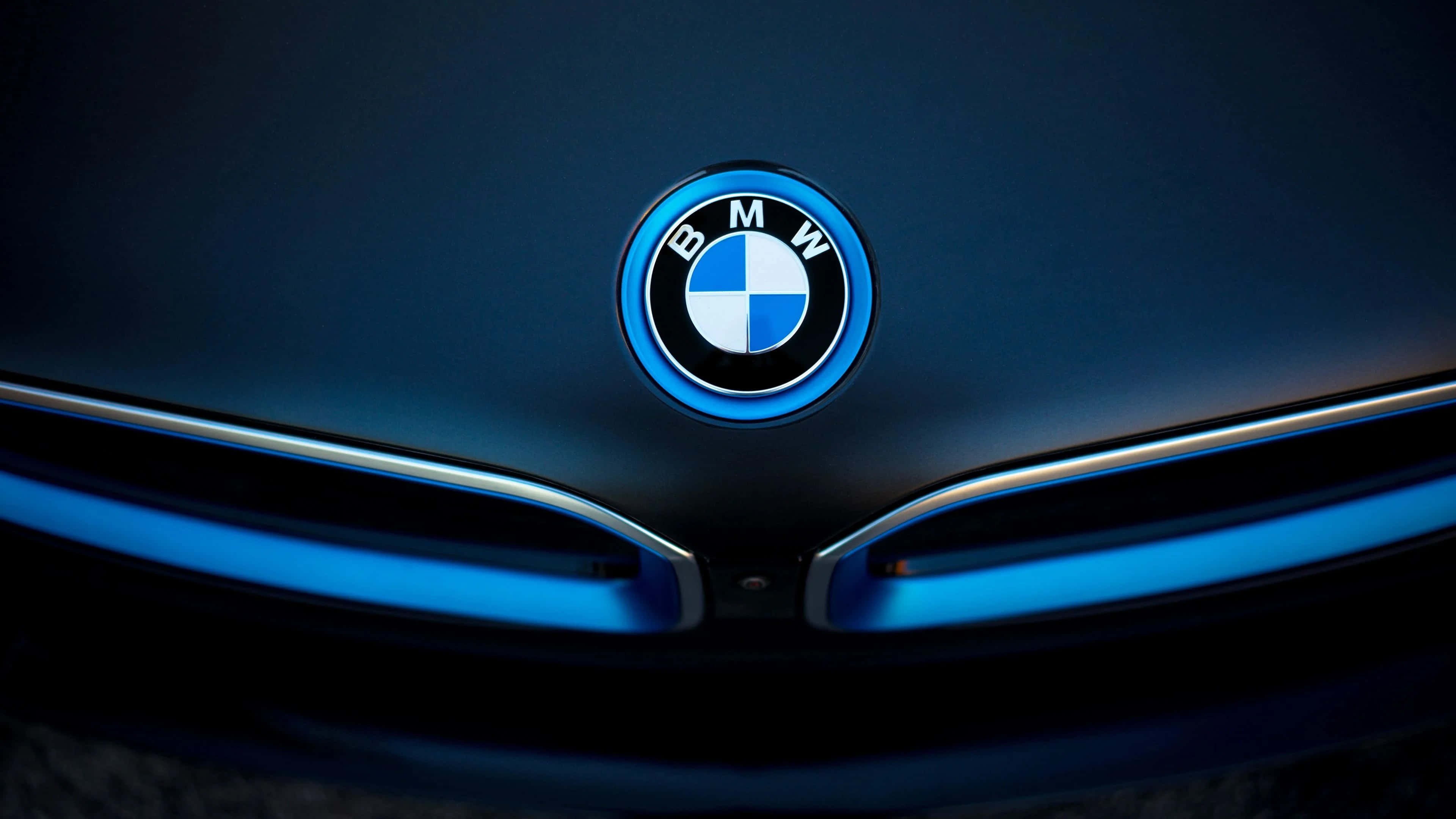 4K BMW 壁紙 桌布 壁紙 — 特寫BMW標誌在戲劇性燈光下於時尚引擎蓋上發出藍光。