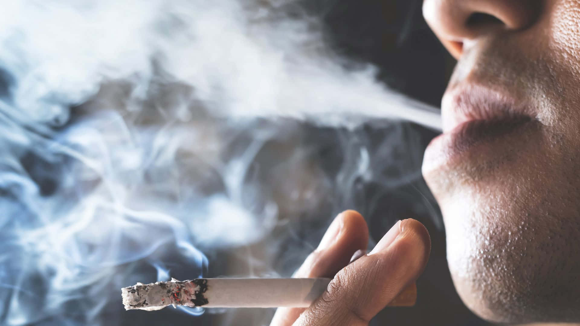 吸煙 桌布 壁紙 — 特寫一個人在黑暗背景下從點燃的香煙中呼出濃煙。