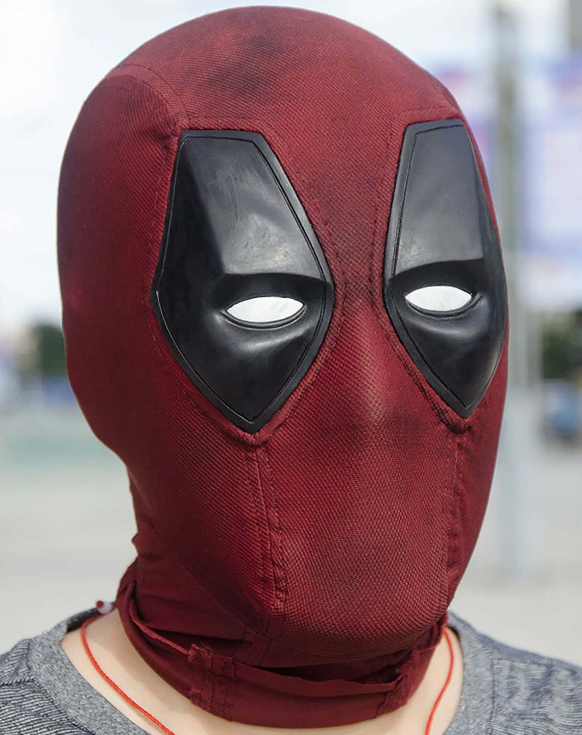 Deadpool Mask 桌布 壁紙 — 特寫一個人戴著帶有紋理的紅色死侍面具，配有黑色眼罩和白色眼孔。