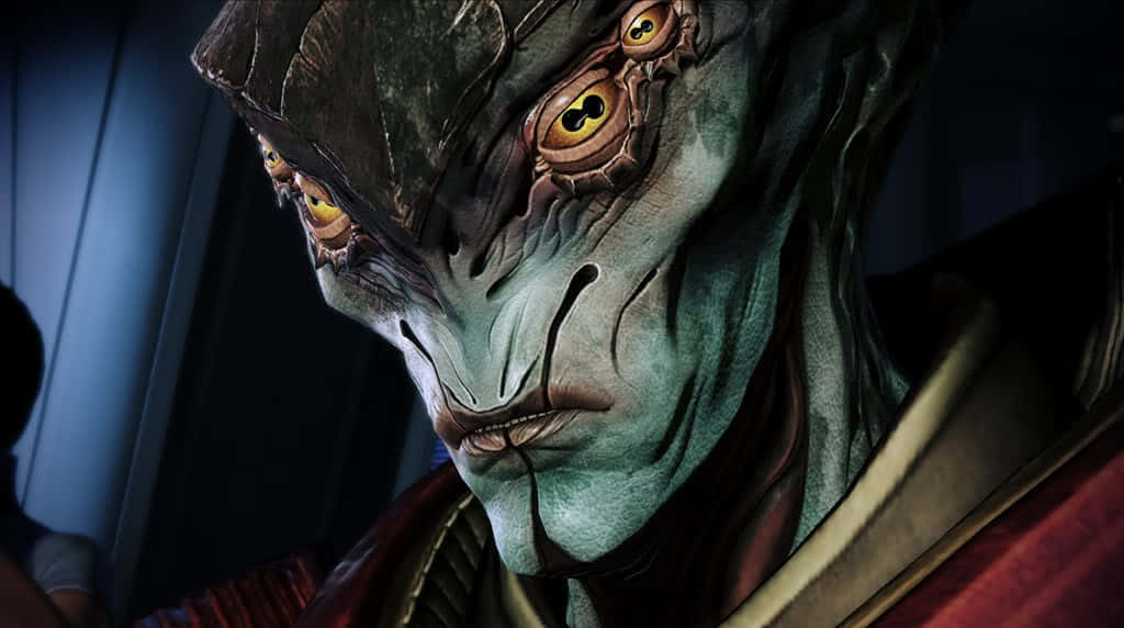 Mass Effect Javik 桌布 壁紙 — 特寫一個在昏暗燈光下、擁有發光黃色眼睛和紋理綠色皮膚的威脅性外星人。
