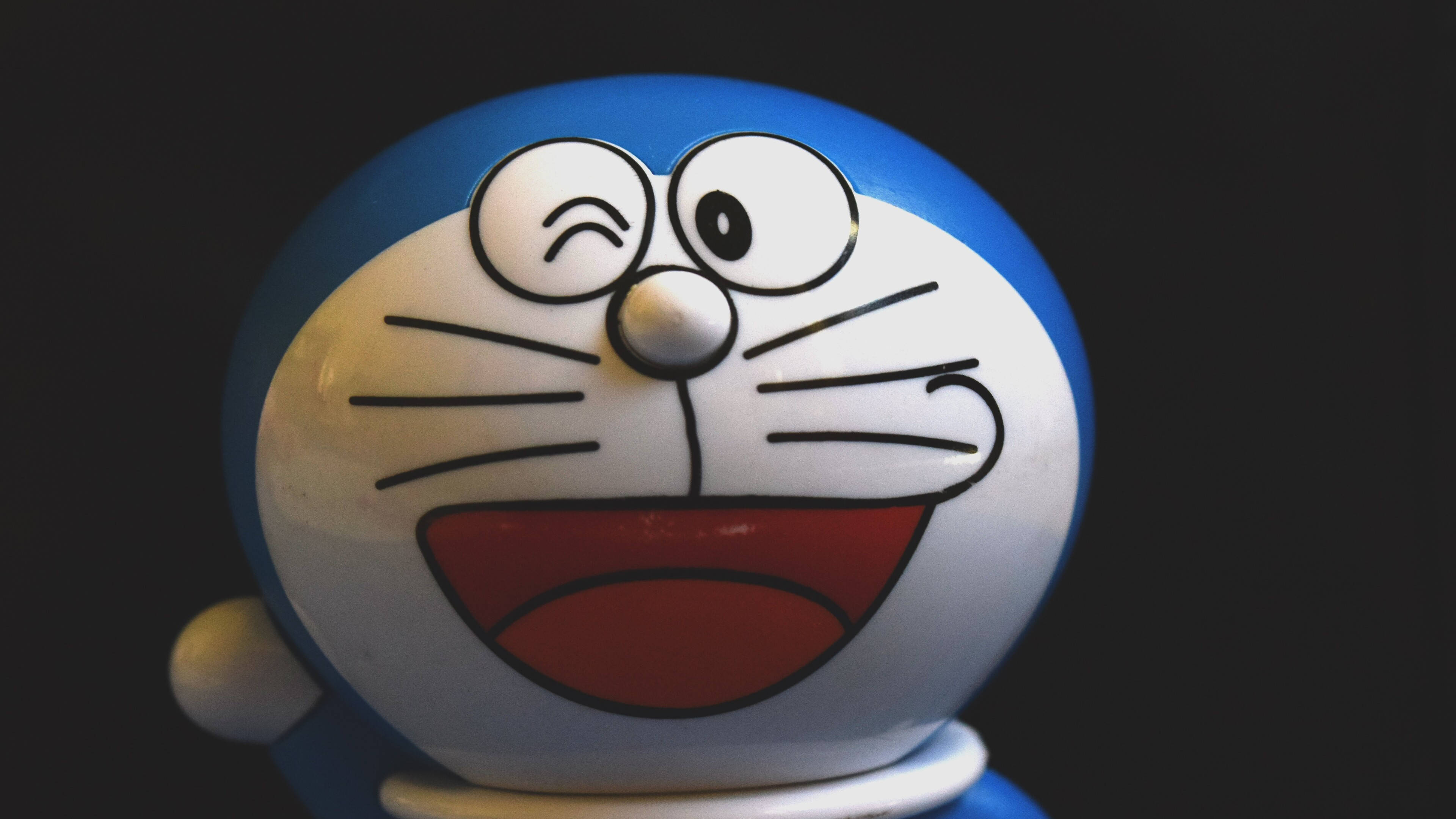 Doraemon 桌布 壁紙 — 特寫一個微笑的藍白色多啦A夢公仔，在深色背景下單眼眨眼。