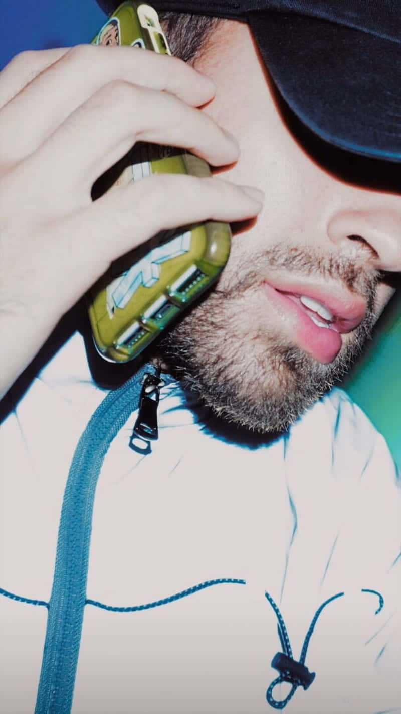  壁紙 — 特寫一個留鬍鬚的男人穿著白色連帽衫，拿著綠色電話貼在耳邊，背景是鮮豔的藍色。