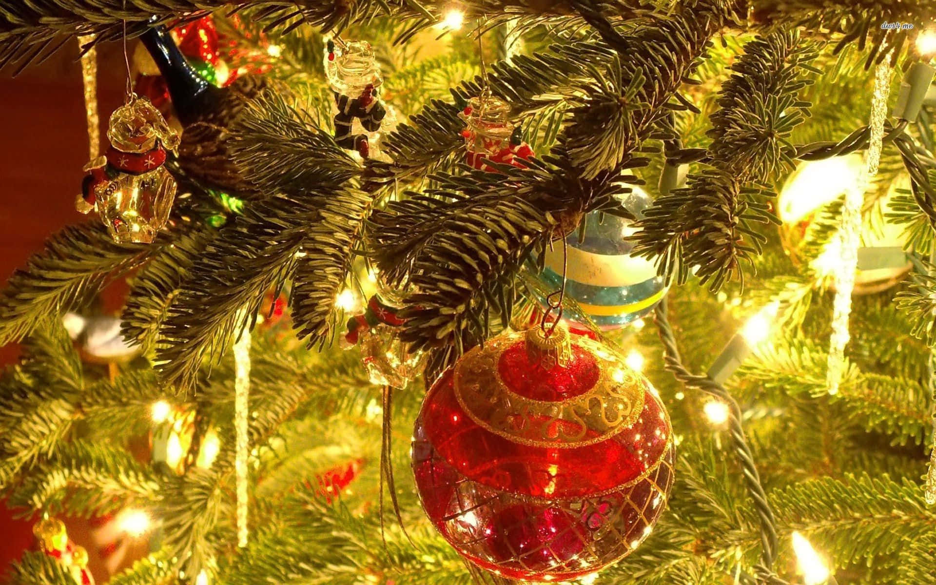 Vintage Christmas 桌布 壁紙 — 特寫一個發光的紅色玻璃裝飾品，掛在裝飾著溫暖童話燈的聖誕樹上。