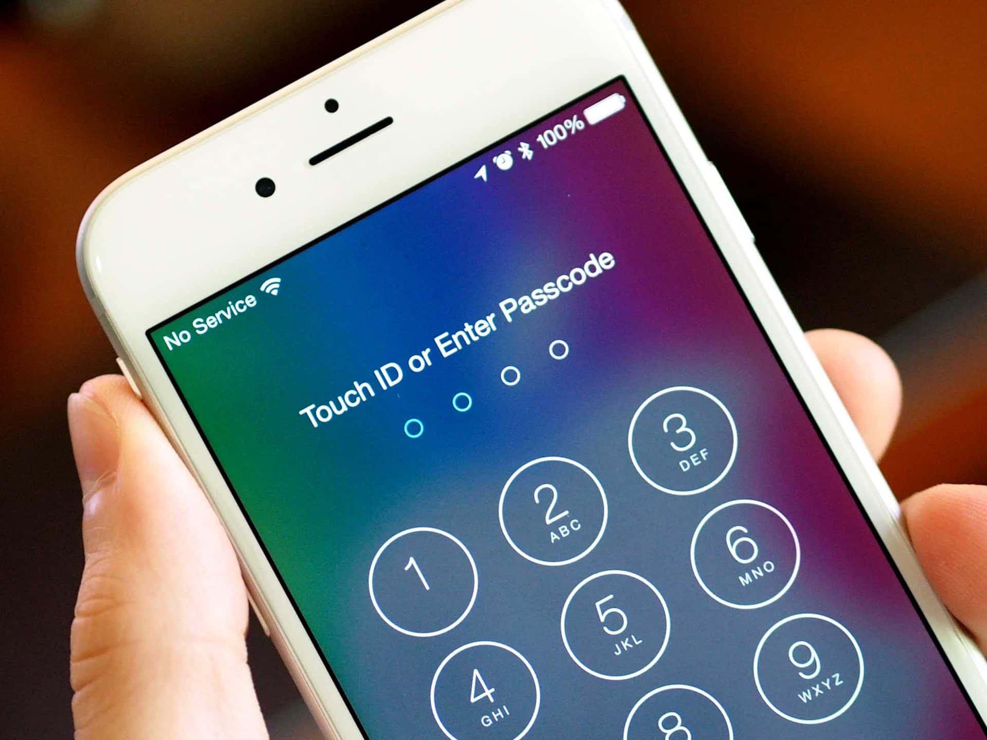 Touch Id 桌布 壁紙 — 特寫一隻手拿著白色iPhone，顯示密碼解鎖畫面，背景為漸變色。