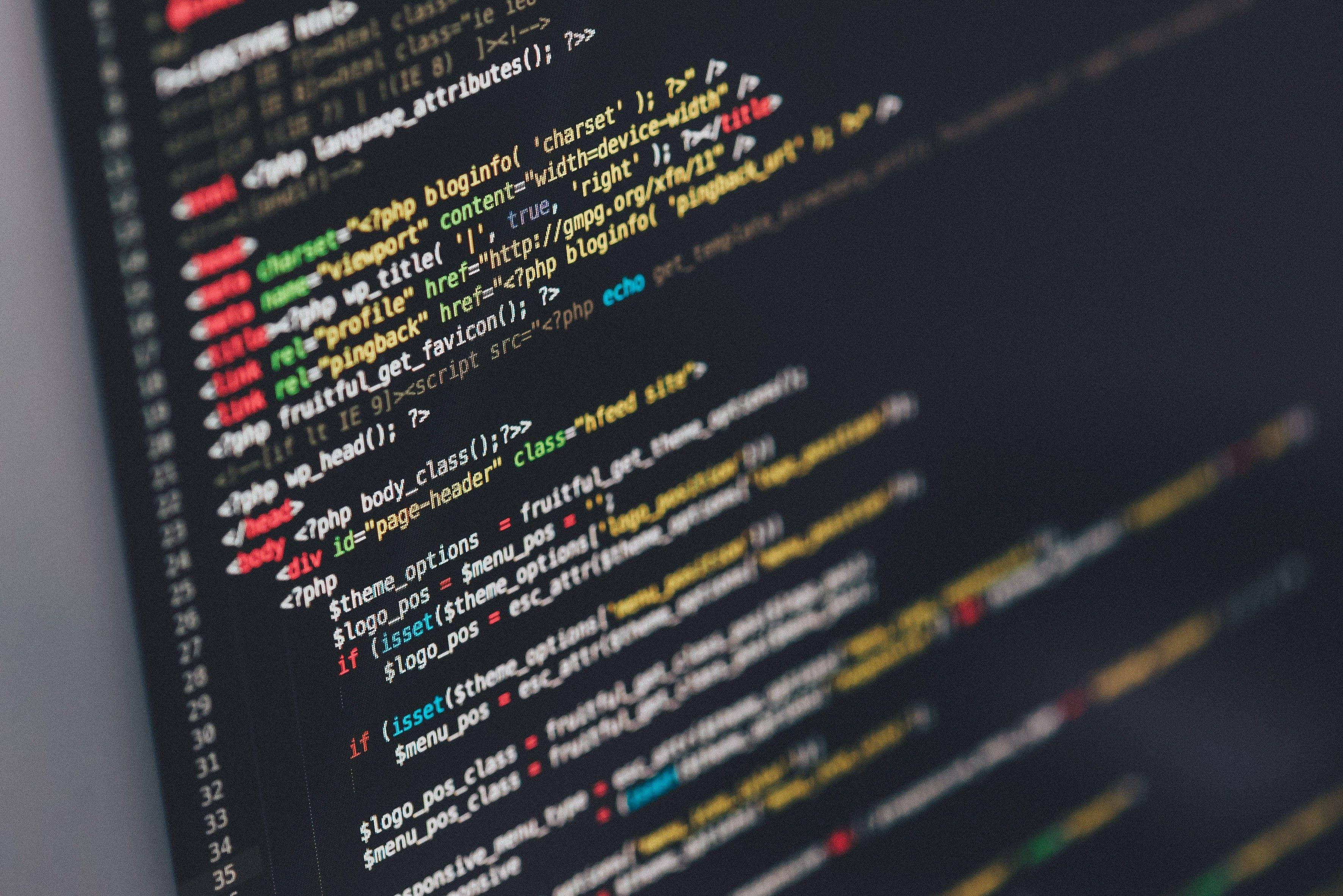 Code 桌布 壁紙 — 特寫彩色 PHP 程式碼在深色電腦螢幕上滾動，背景模糊。