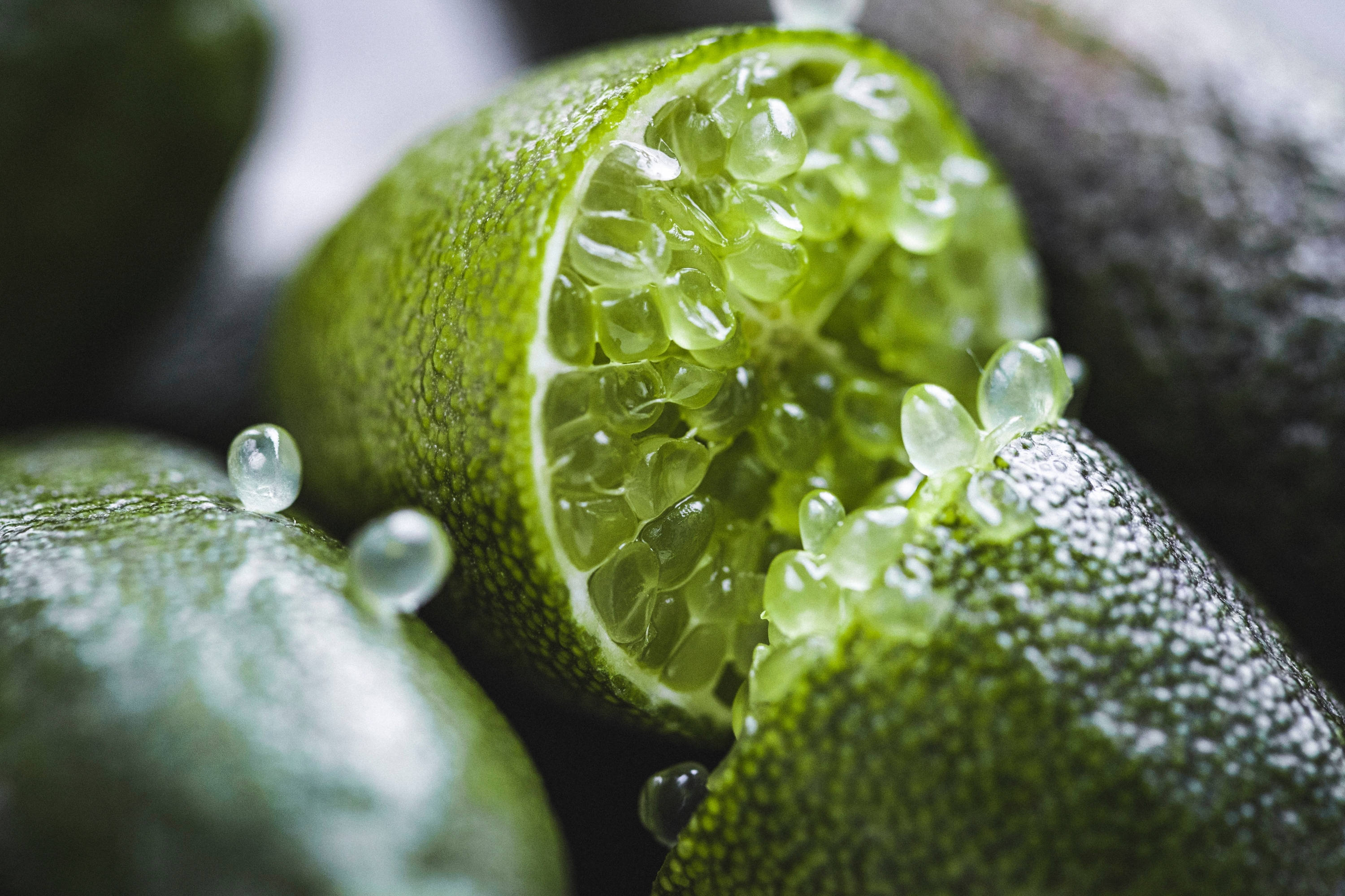 特寫指 lime 果 壁紙 — 半個青檸的特寫，露出閃閃發光的半透明果肉，水滴附著在紋理清晰的綠色外皮上。