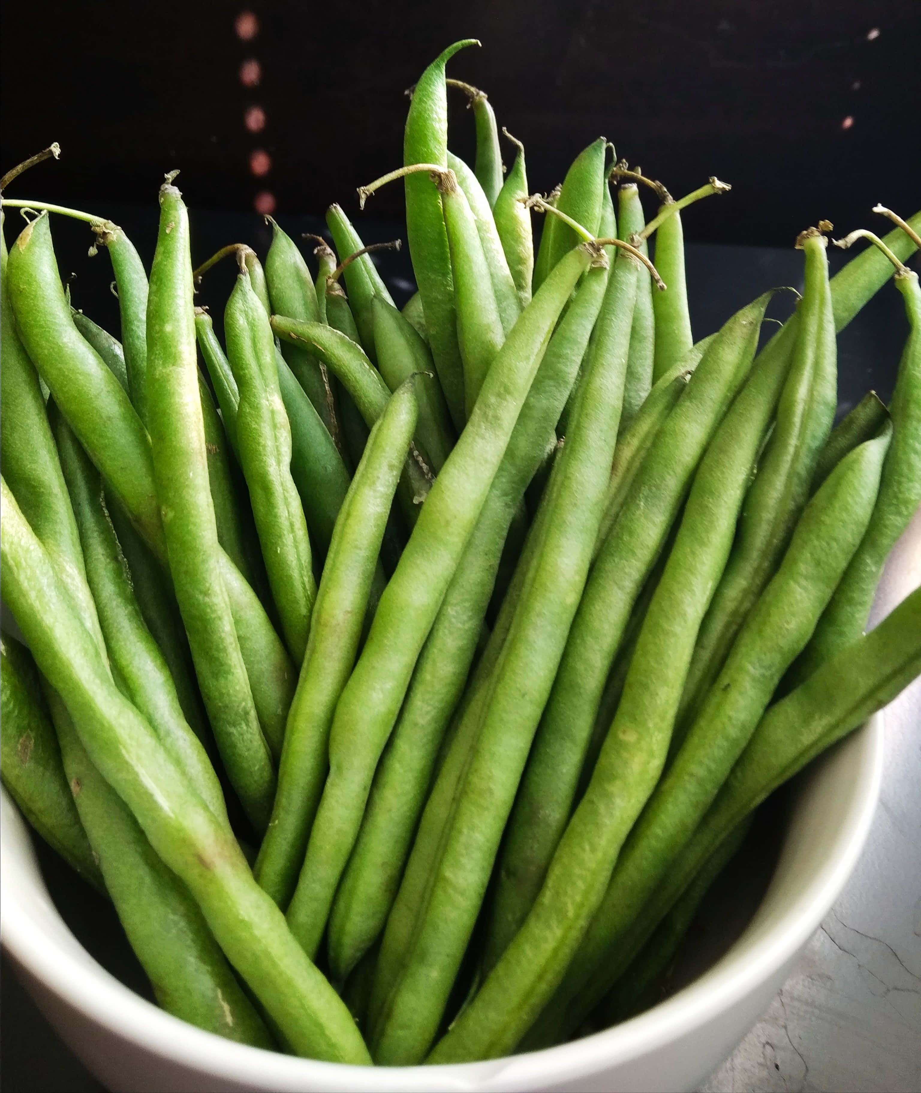 beans 桌布 壁紙 — 特寫新鮮翠綠的豆角高高堆在白色陶瓷碗中，背景深色。