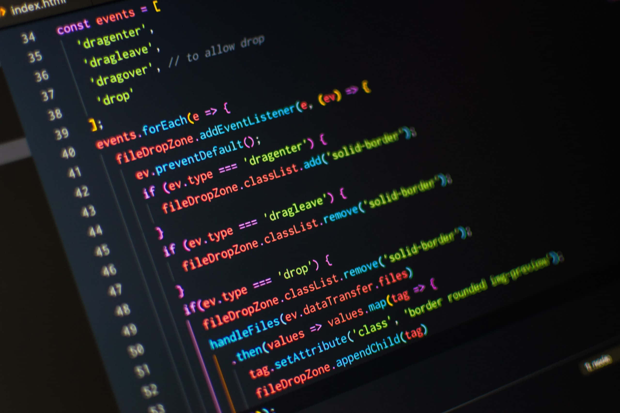程式碼 桌布 壁紙 — 特寫發光的彩色程式碼行在深色螢幕上，展示 JavaScript 拖放事件處理。