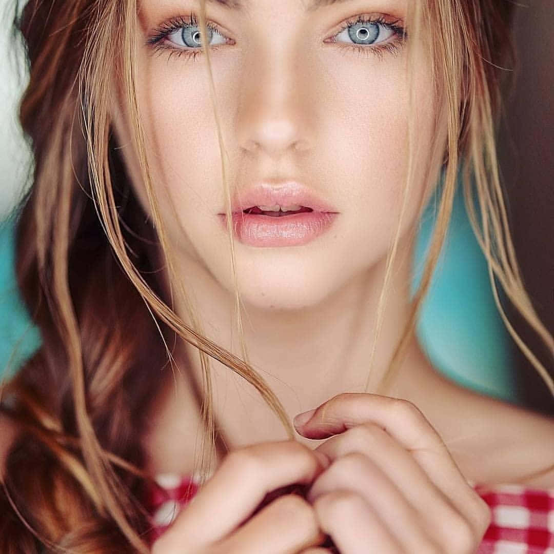 Beautiful Girls 桌布 壁紙 — 特寫肖像，一位擁有引人注目的藍色眼睛和鬆散金髮的女性，背景為青綠色。
