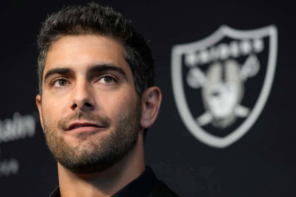 Jimmy Garoppolo 桌布 壁紙 — 特寫肖像，一名深色頭髮和鬍鬚的男子在黑色背景上向上看，背景上有白色的奧克蘭突襲者隊標誌。