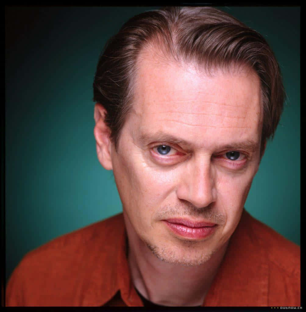 steve buscemi 桌布 壁紙 — 特寫肖像，一名男子擁有強烈的藍色眼睛和向後梳的頭髮，背景為青綠色。