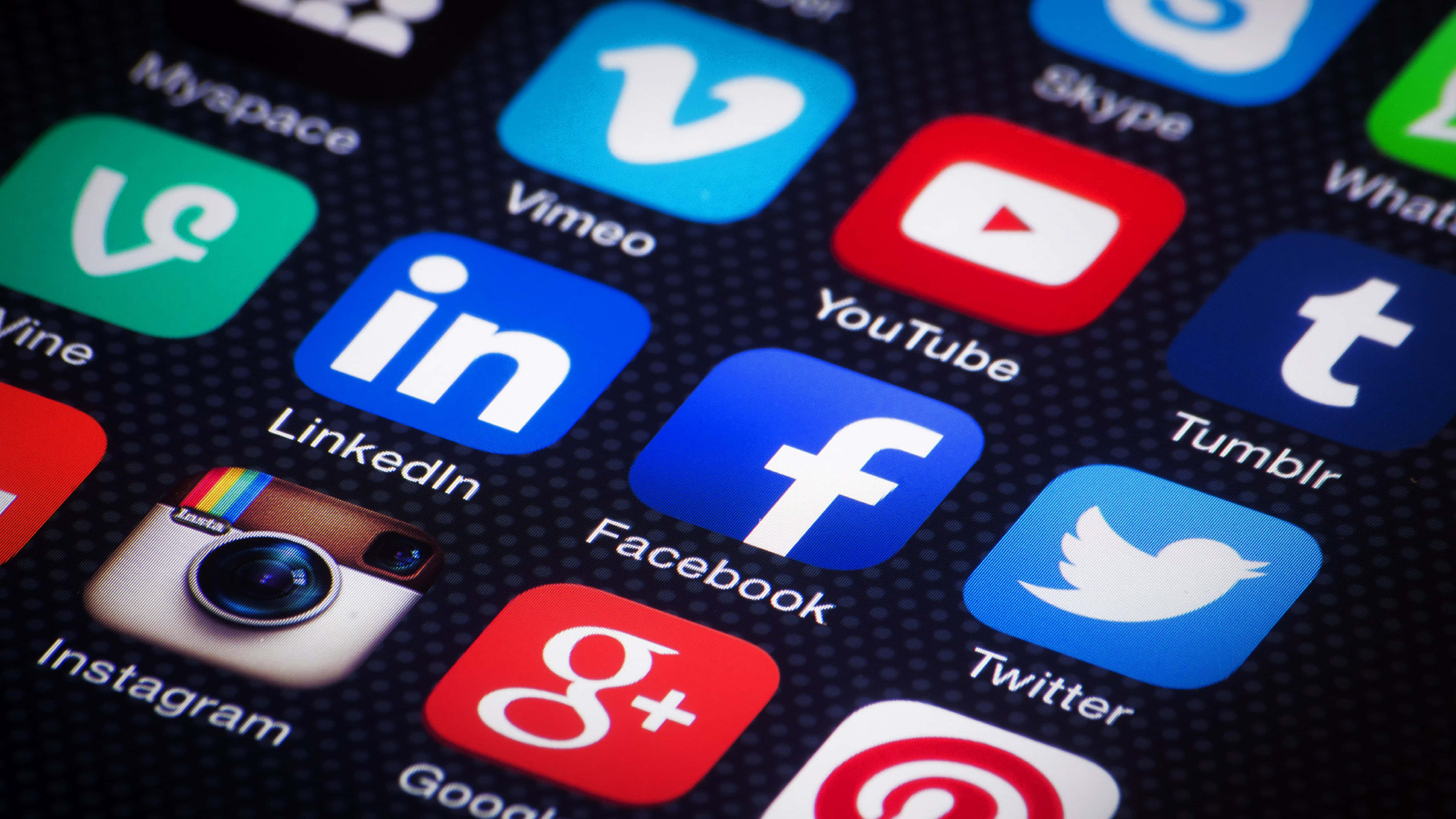 4K Social Media 桌布 壁紙 — 特寫色彩繽紛的社交媒體應用程式圖標在智能手機屏幕上發光，背景為深色紋理。