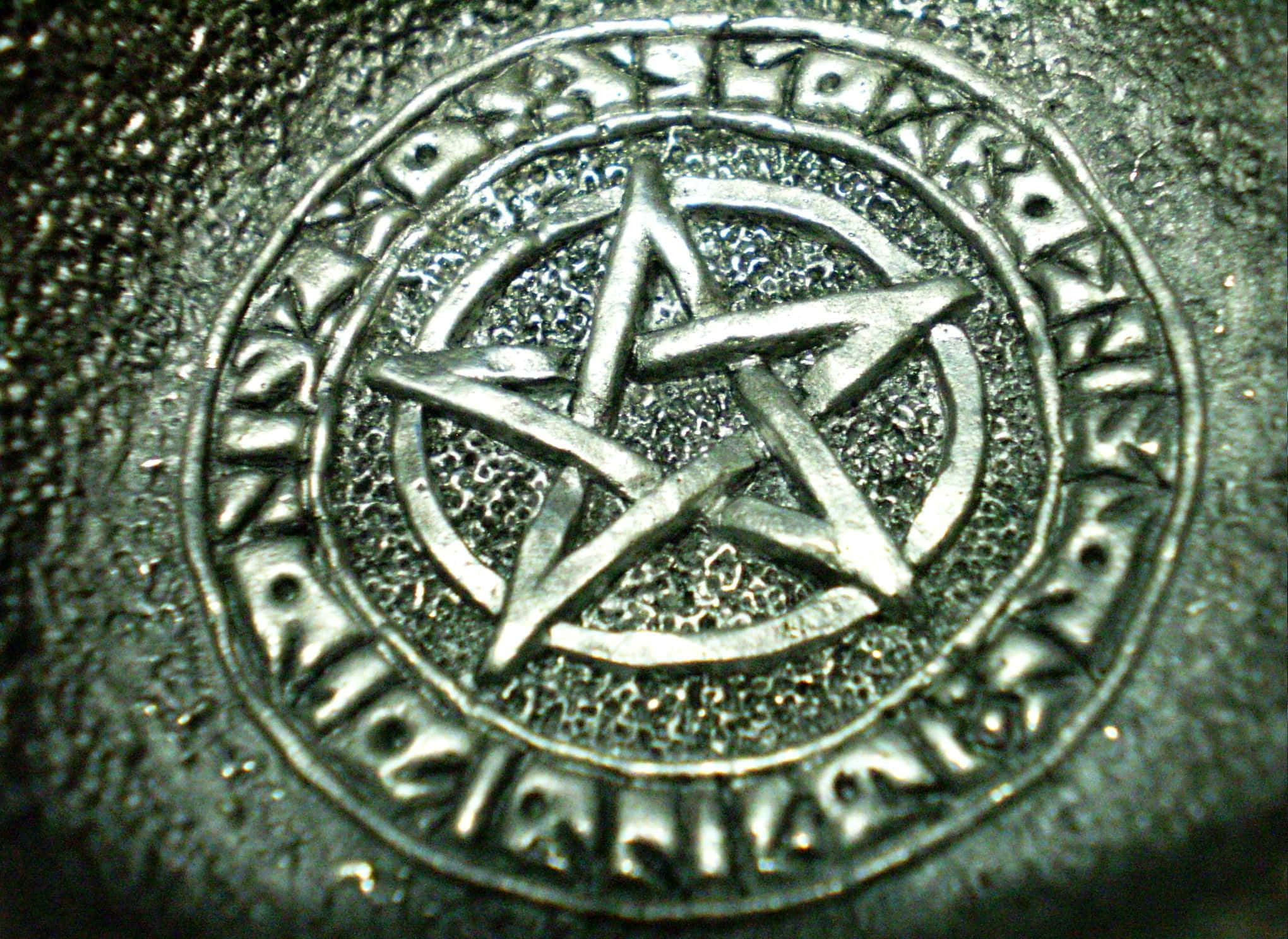 Pagan 桌布 壁紙 — 特寫鏡頭：一個金屬五角星符號，刻在一個由古代符文組成的圓形邊框內，表面帶有紋理。