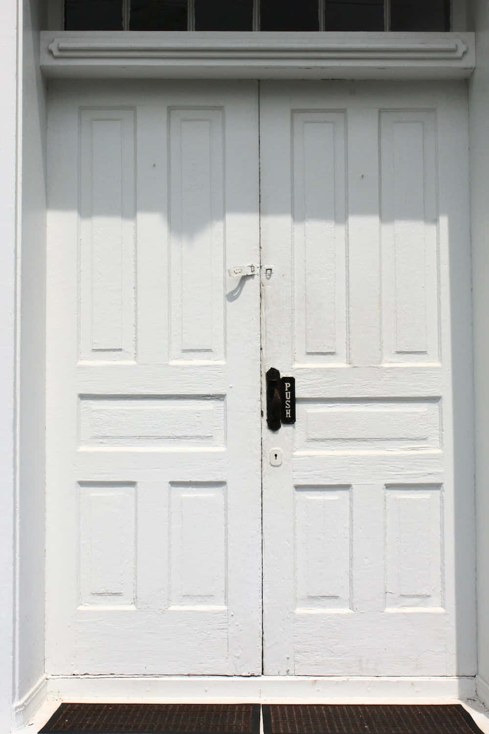 Door 桌布 壁紙 — 特寫鏡頭：一扇歷經風霜的白色雙門，配有黑色推拉手柄和門閂，在明亮的日光下。