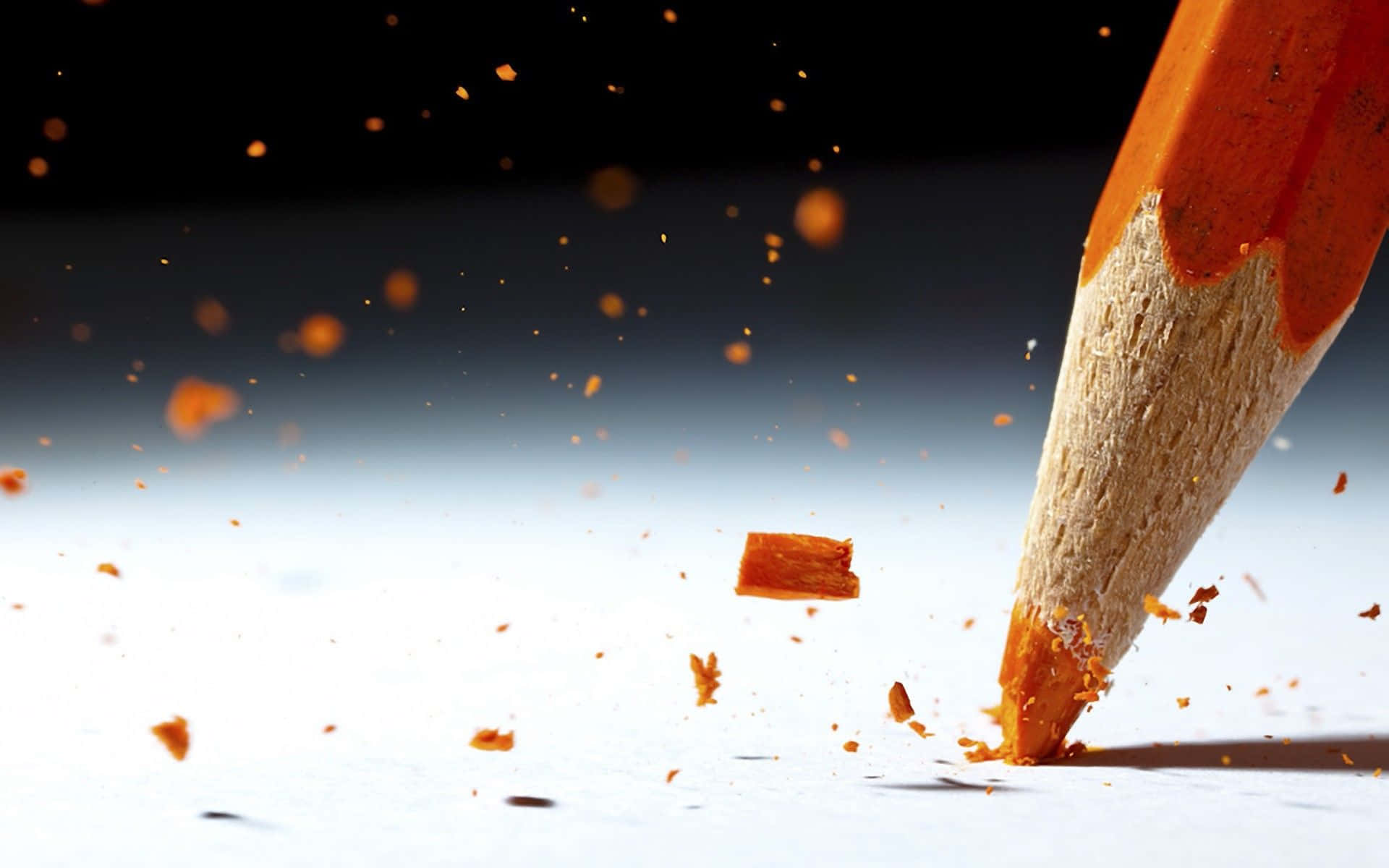 pencil 桌布 壁紙 — 特寫鏡頭：一支削尖的橙色鉛筆在深色漸變背景下的白紙上書寫，木屑飛揚。