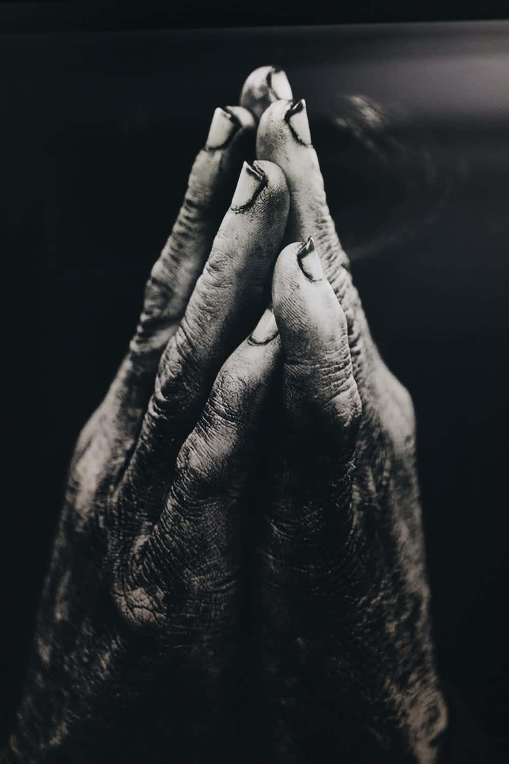 Praying 桌布 壁紙 — 特寫鏡頭：一雙飽經風霜的手在黑暗背景中合十祈禱，光線柔和。