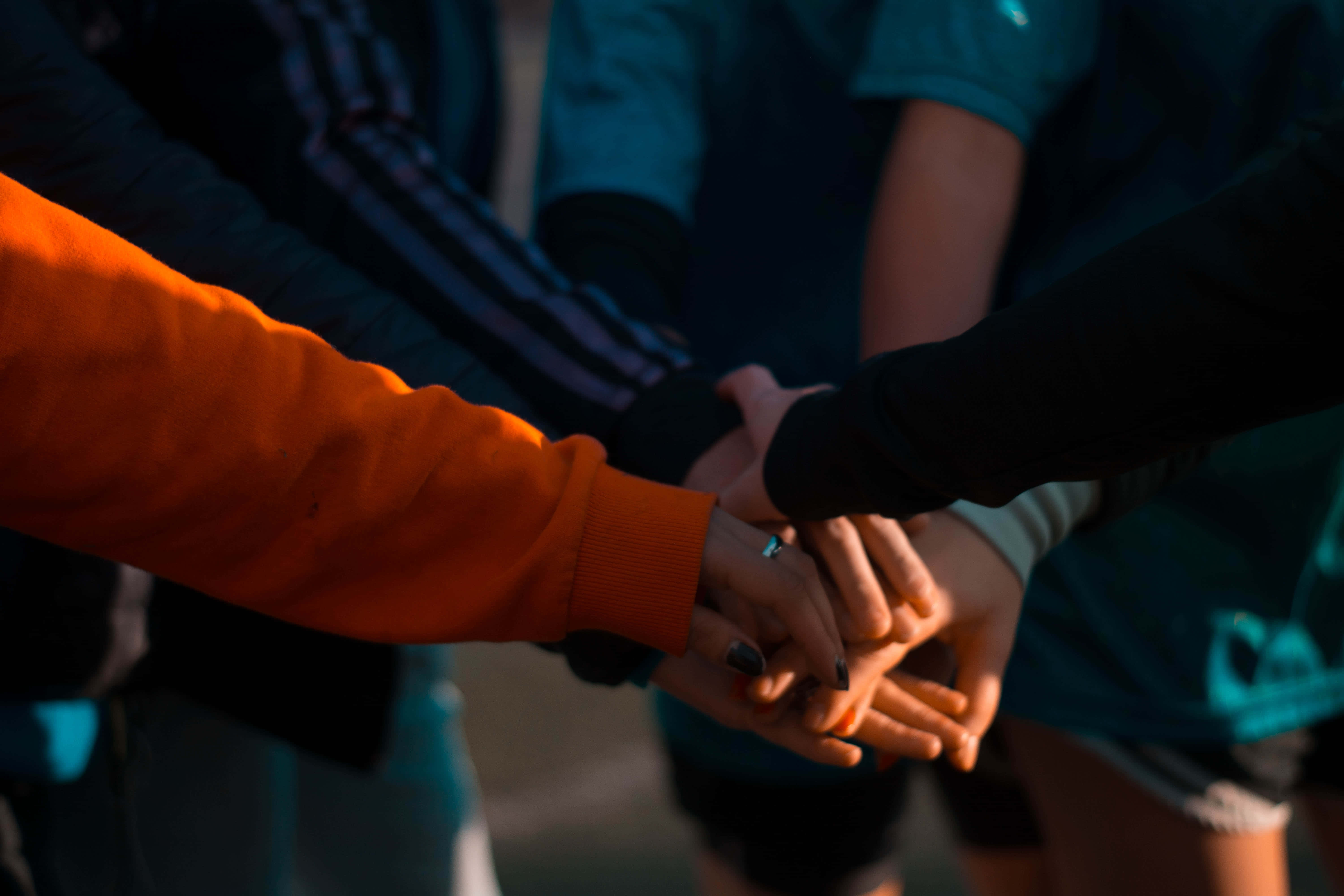 hands 桌布 壁紙 — 特寫鏡頭，不同膚色的手疊成一個圓圈，在溫暖的陽光下展現團結與團隊合作。