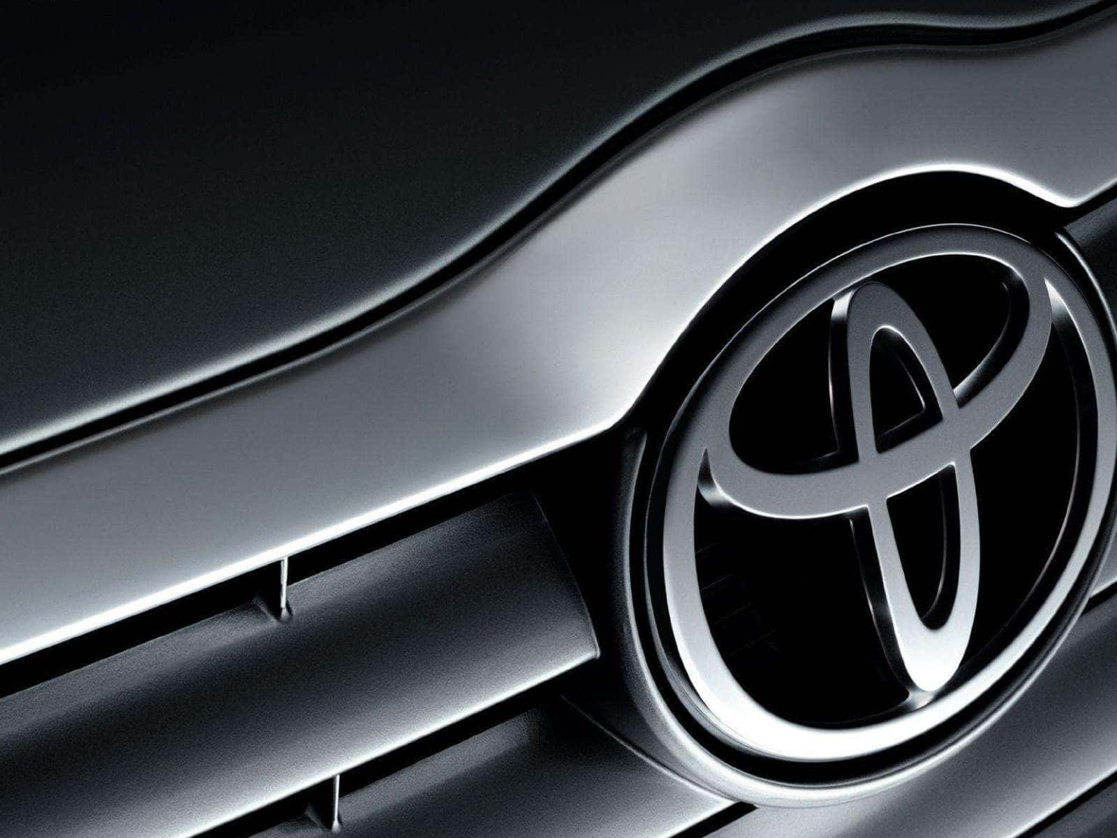 Toyota 桌布 壁紙 — 特寫鏡頭：在工作室燈光下，深色汽車格柵上閃耀的時尚銀色豐田標誌。