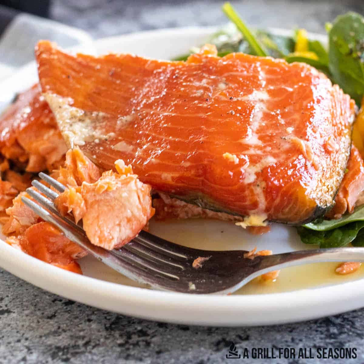 Salmon 桌布 壁紙 — 特寫鏡頭：多汁烤三文魚柳，肉質呈片狀，置於白色碟上，伴以蔬菜及叉子。