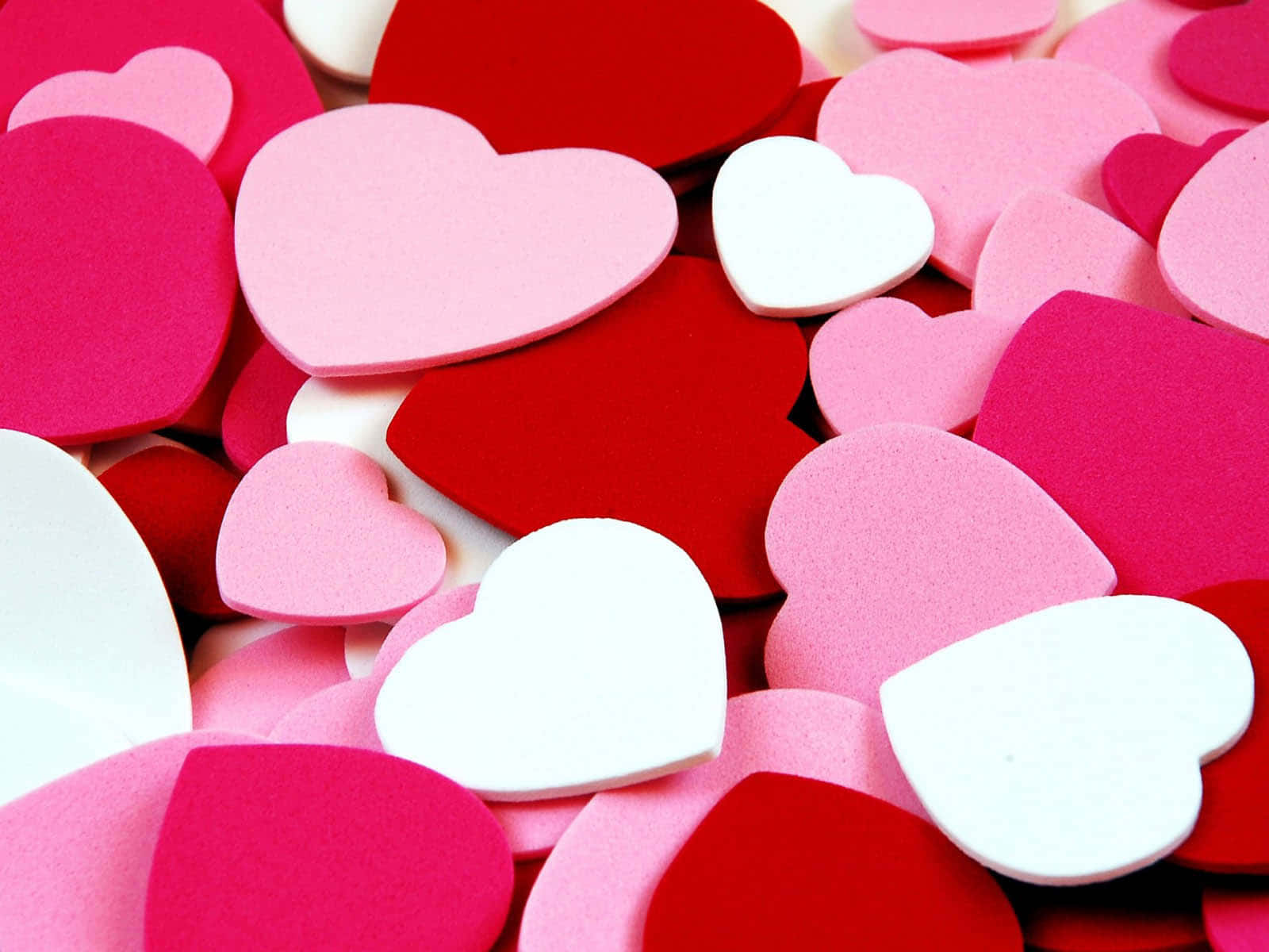 3d Heart 桌布 壁紙 — 特寫鏡頭，散落的紅色、粉紅色和白色泡沫心形，營造出柔軟有質感的情人節背景。