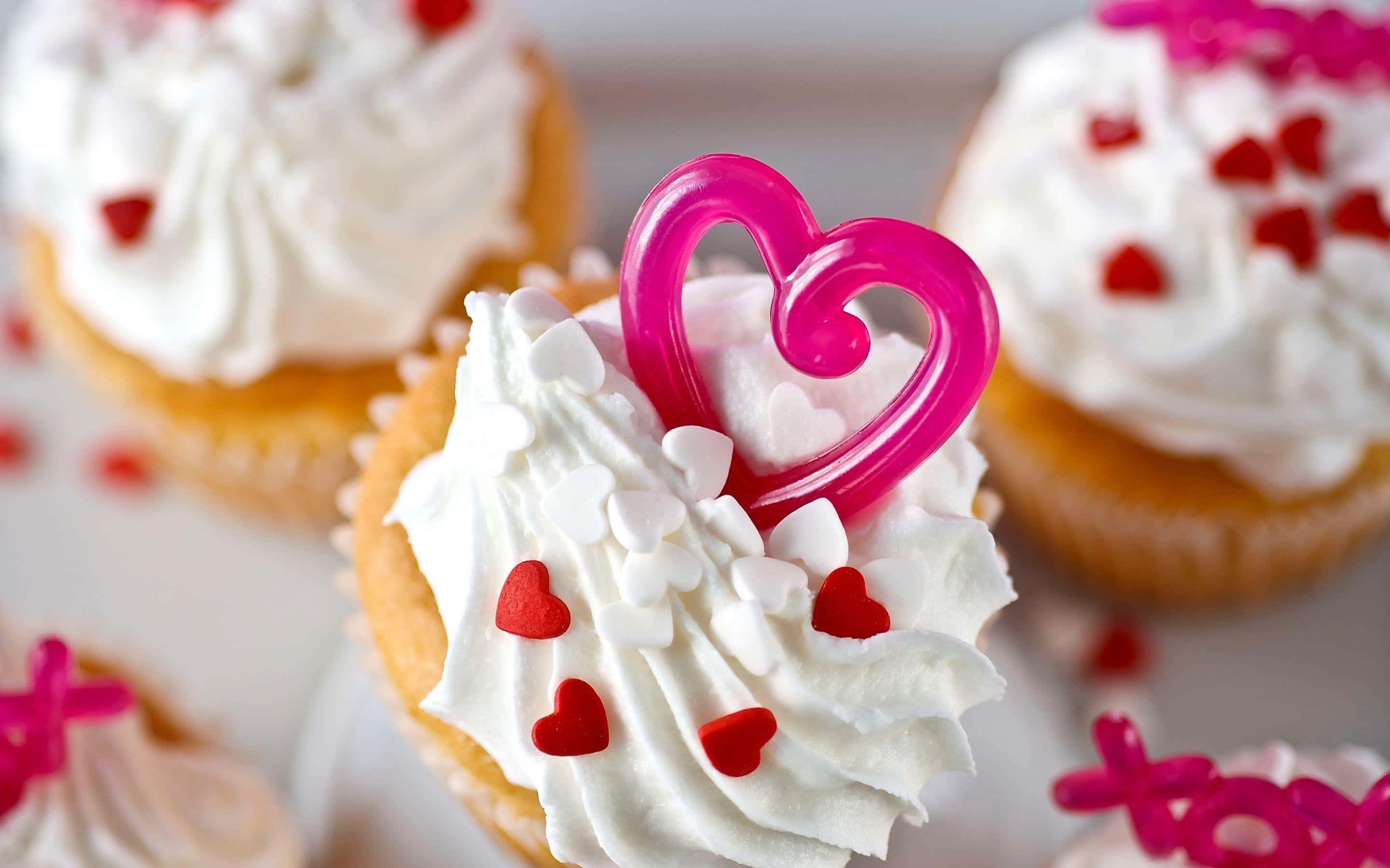 Cute Cupcake 桌布 壁紙 — 特寫鏡頭：杯子蛋糕上鋪著白色糖霜，撒上紅色心形糖粒，並放上粉紅色心形裝飾。