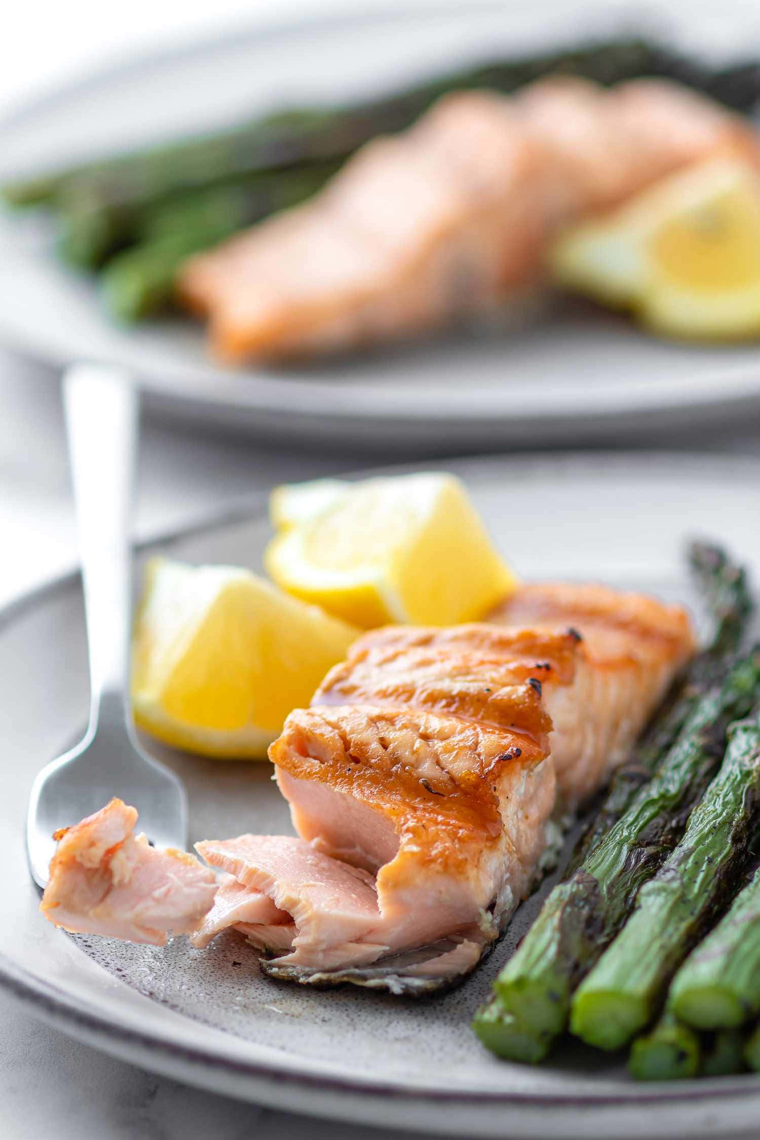 Salmon 桌布 壁紙 — 特寫鏡頭：烤三文魚配檸檬角及蘆筍，置於灰色碟上，附有叉子。