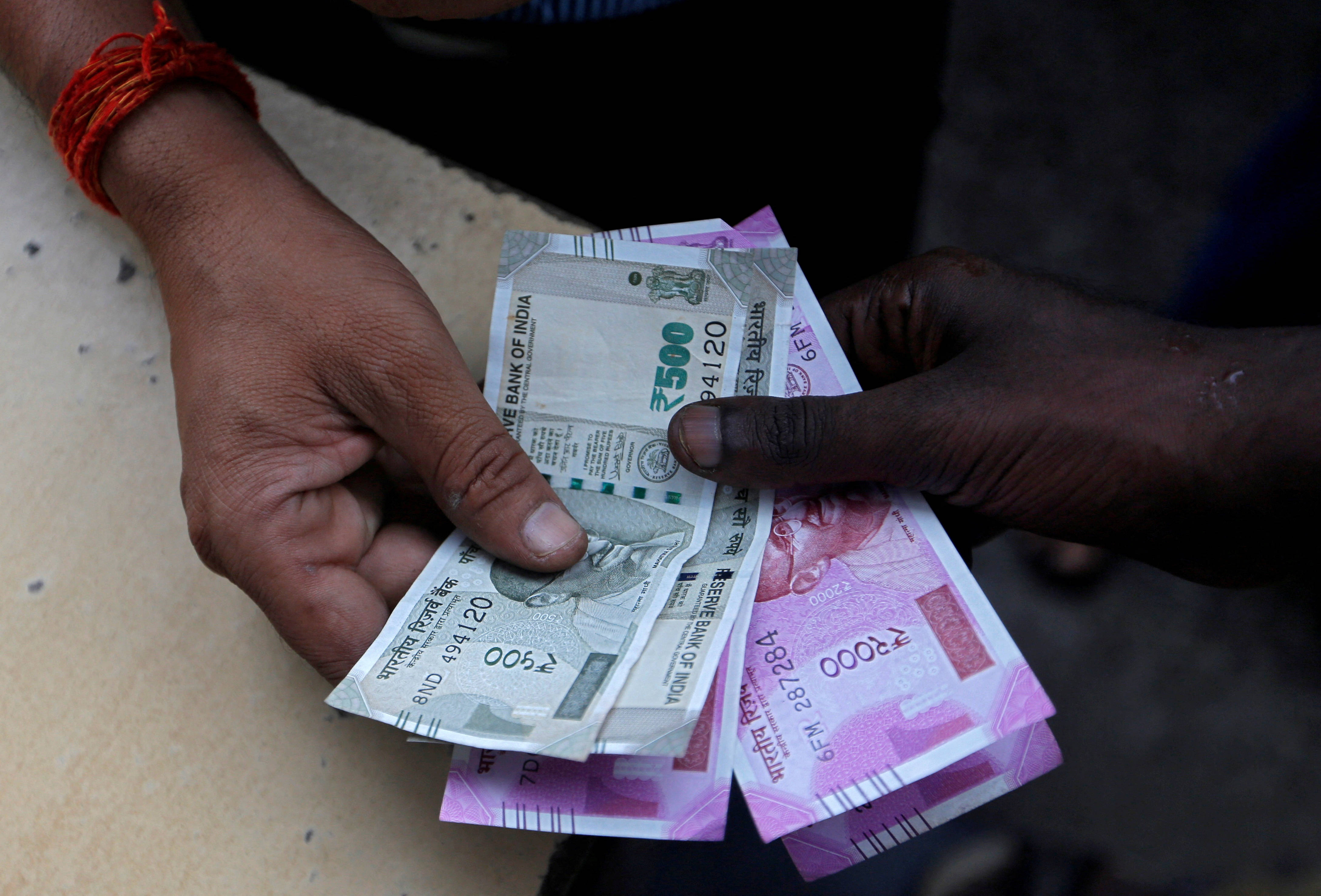 Indian 桌布 壁紙 — 特寫鏡頭：粗糙雙手交換印度盧比紙幣，可見面額及紅線手繩。