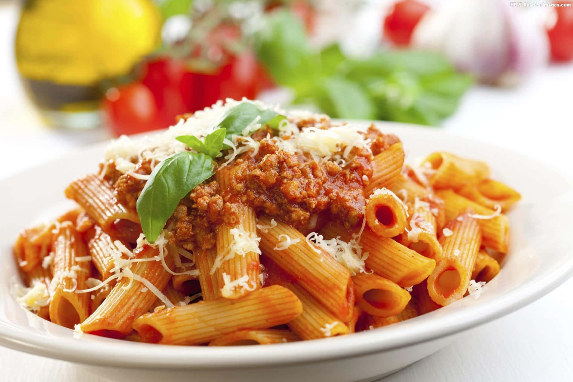 Pasta 桌布 壁紙 — 特寫鏡頭：長通粉配濃郁肉醬，灑上磨碎芝士和新鮮羅勒葉。