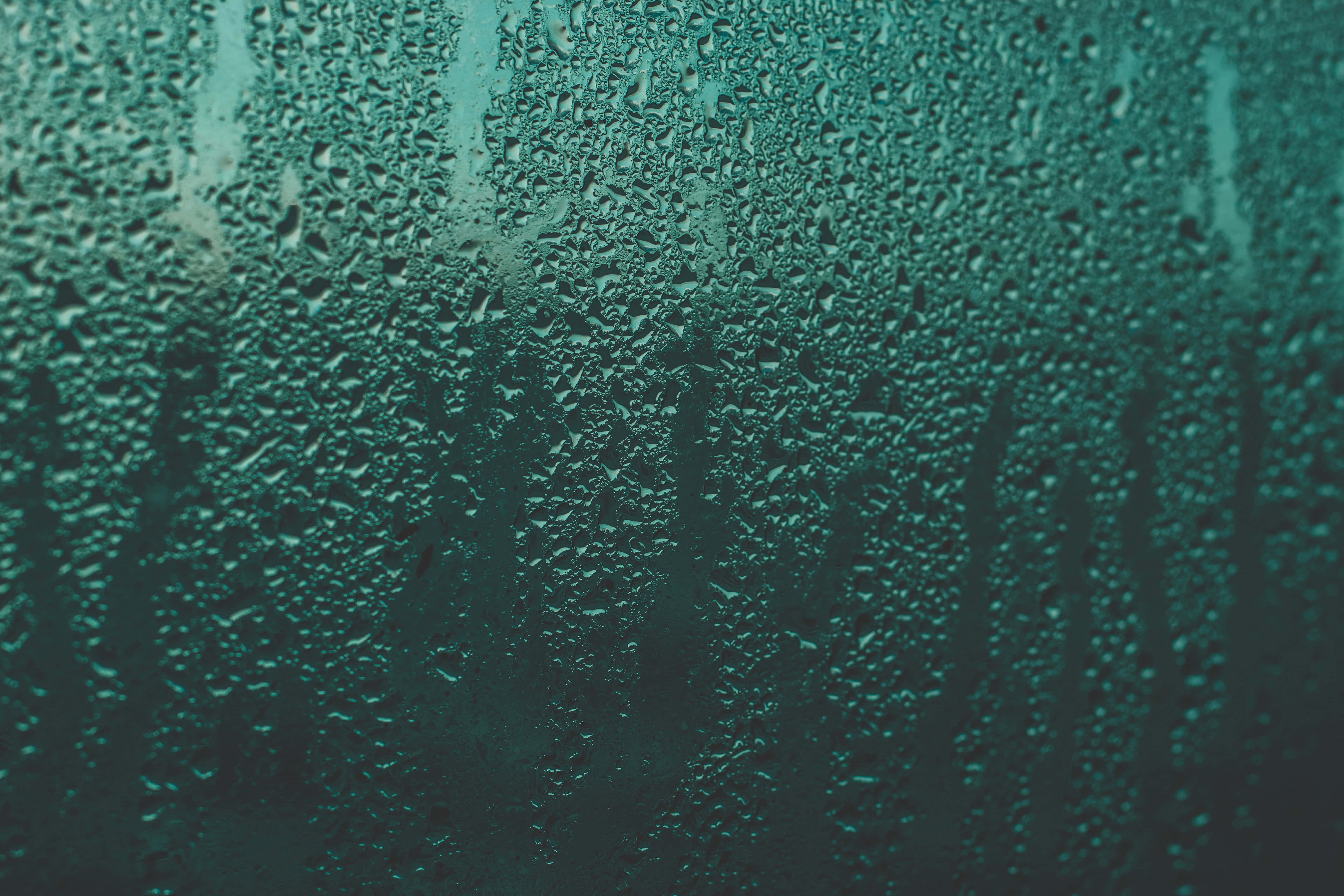 Liquid 桌布 壁紙 — 特寫鏡頭：雨滴依附在帶有青綠色調的玻璃表面，背景模糊。