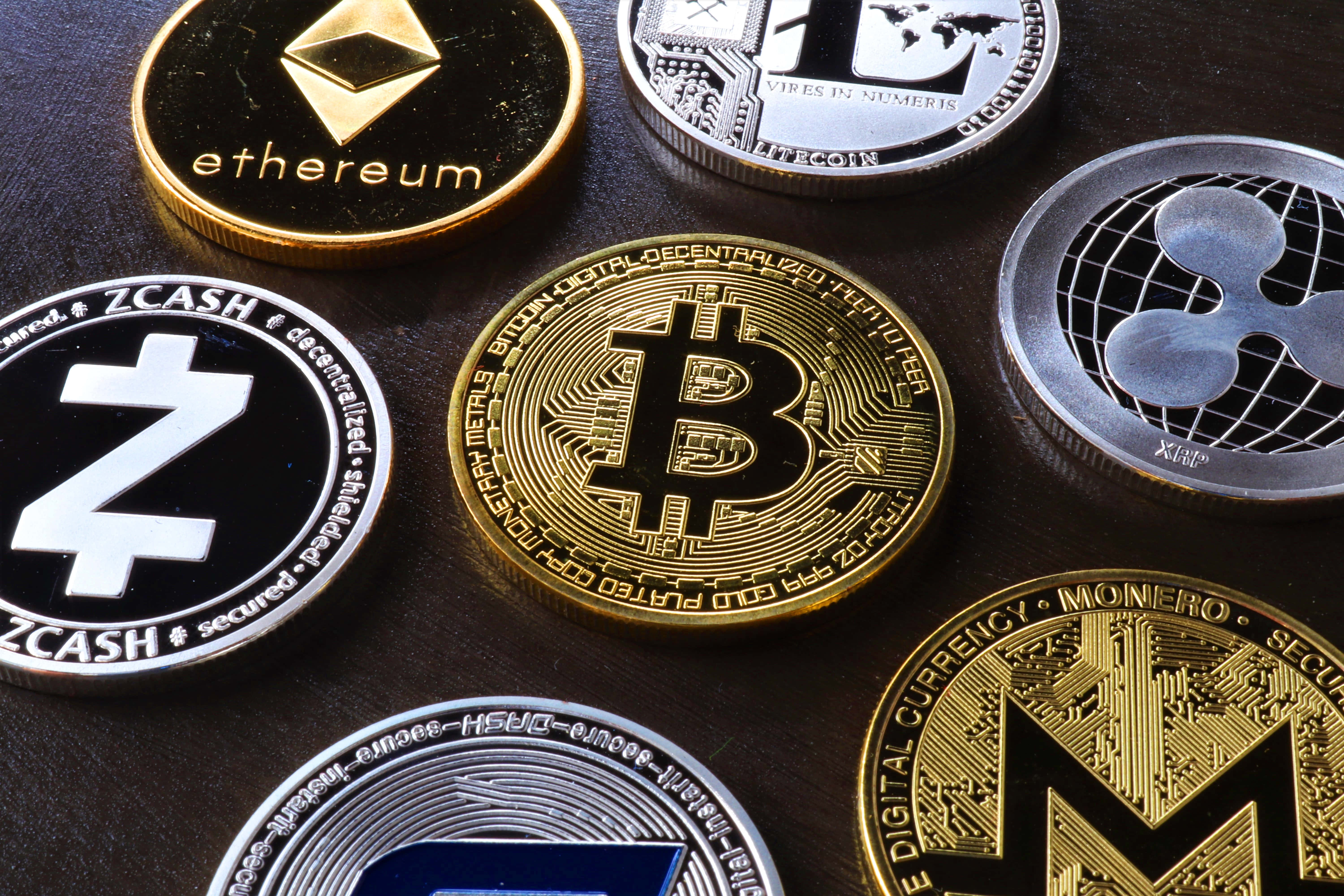 Mining 桌布 壁紙 — 特寫鏡頭展示實體加密貨幣硬幣，包括比特幣、以太坊和Zcash，排列在深色紋理表面上。