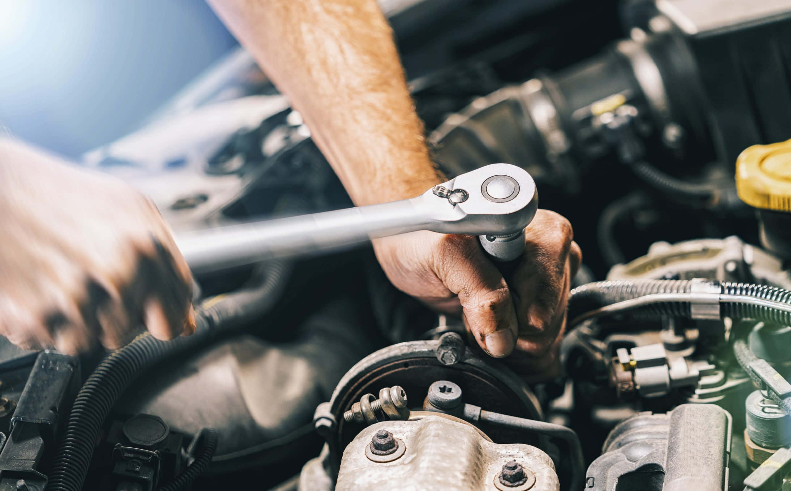 Car Repair 桌布 壁紙 — 特寫鏡頭顯示機械師的手在明亮光線下使用套筒扳手擰緊汽車引擎上的螺栓。