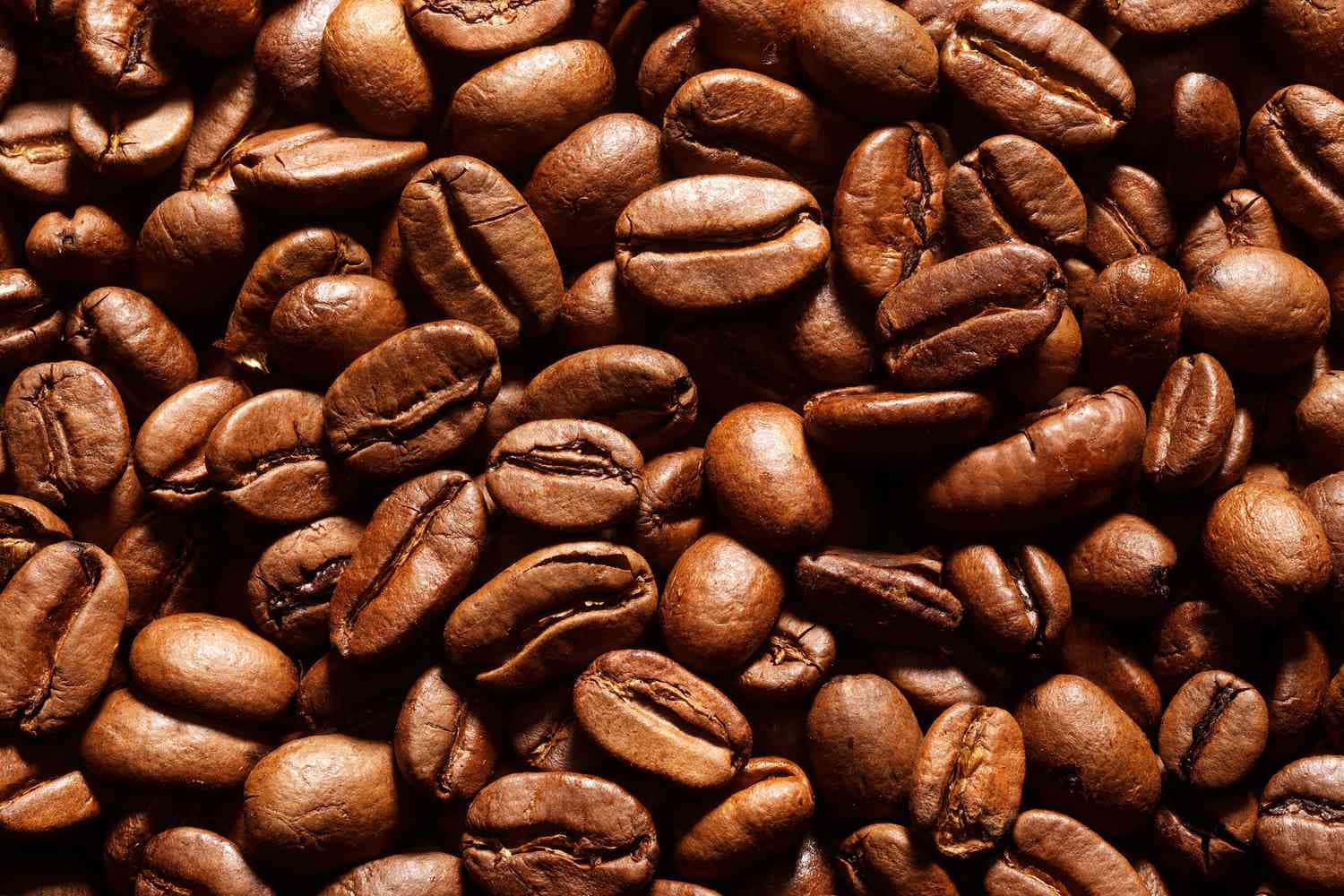 Brown Coffee 桌布 壁紙 — 特寫鏡頭顯示豐富烘焙的咖啡豆，表面光滑棕色，帶有深裂紋。