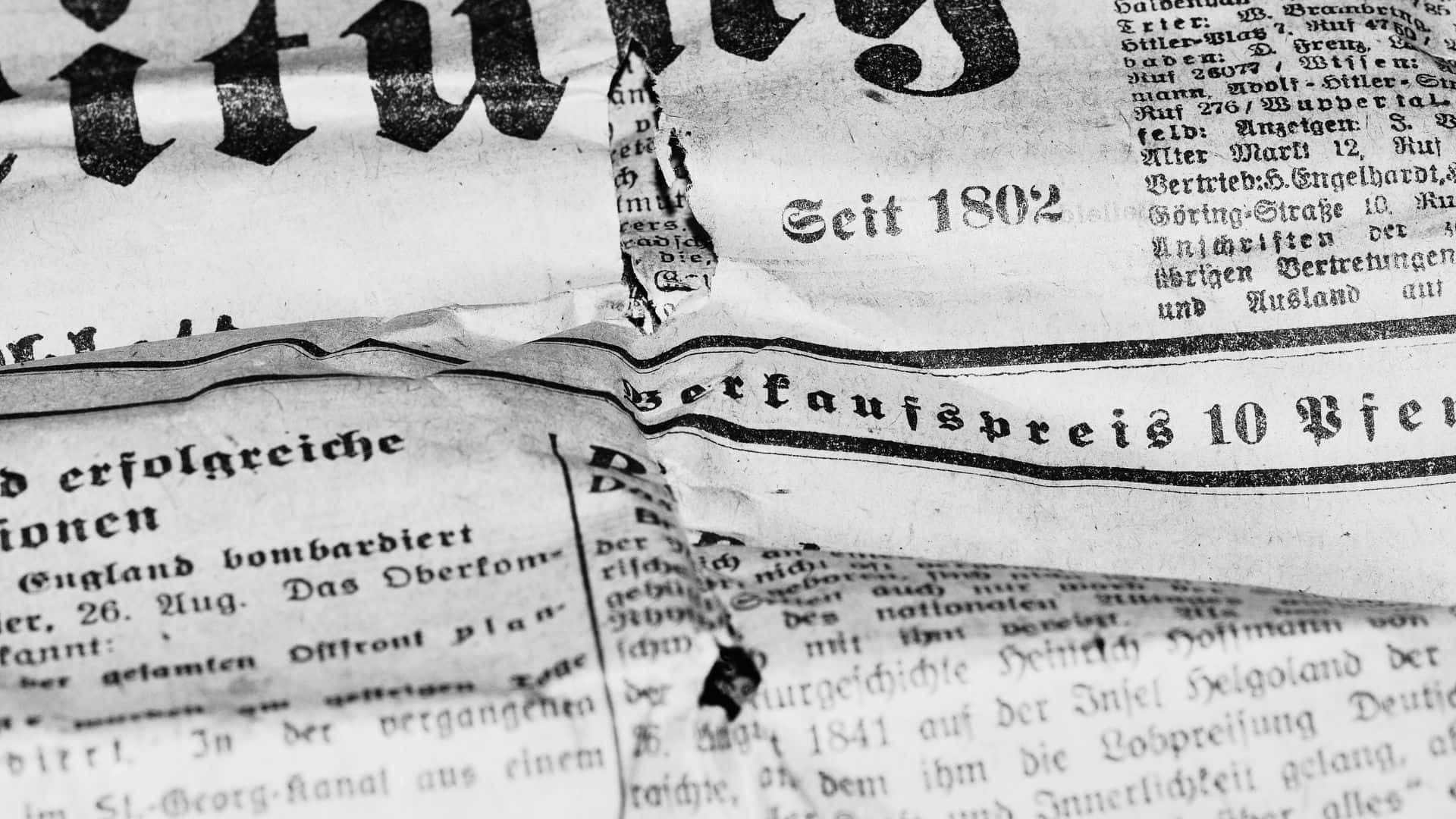 Black And White Newspaper 桌布 壁紙 — 特寫陳舊的德國報紙頁面，邊緣破損，黑色墨水文字褪色。