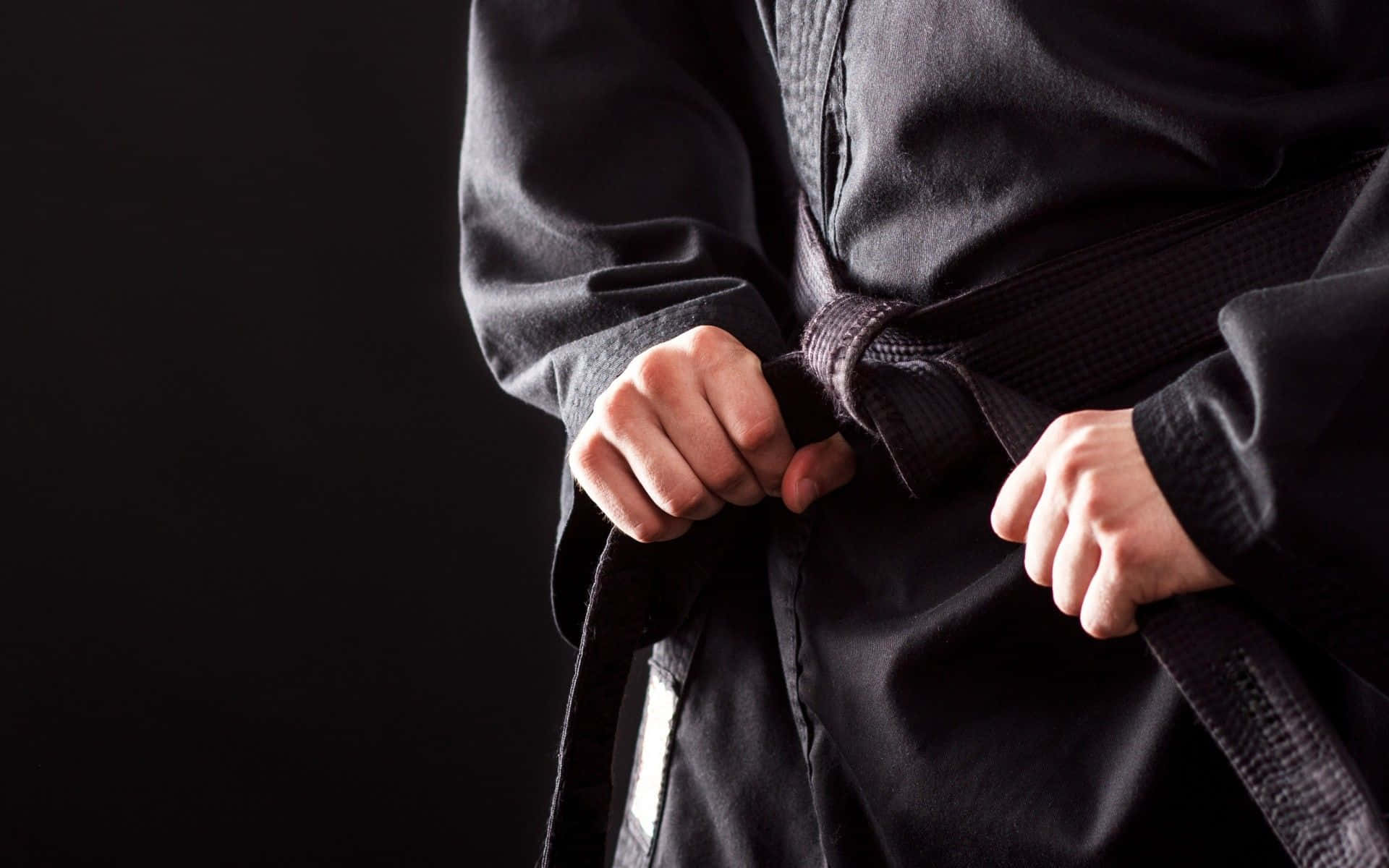 Martial Arts Uniform 桌布 壁紙 — 特寫雙手在深色背景下緊握黑色武術腰帶。