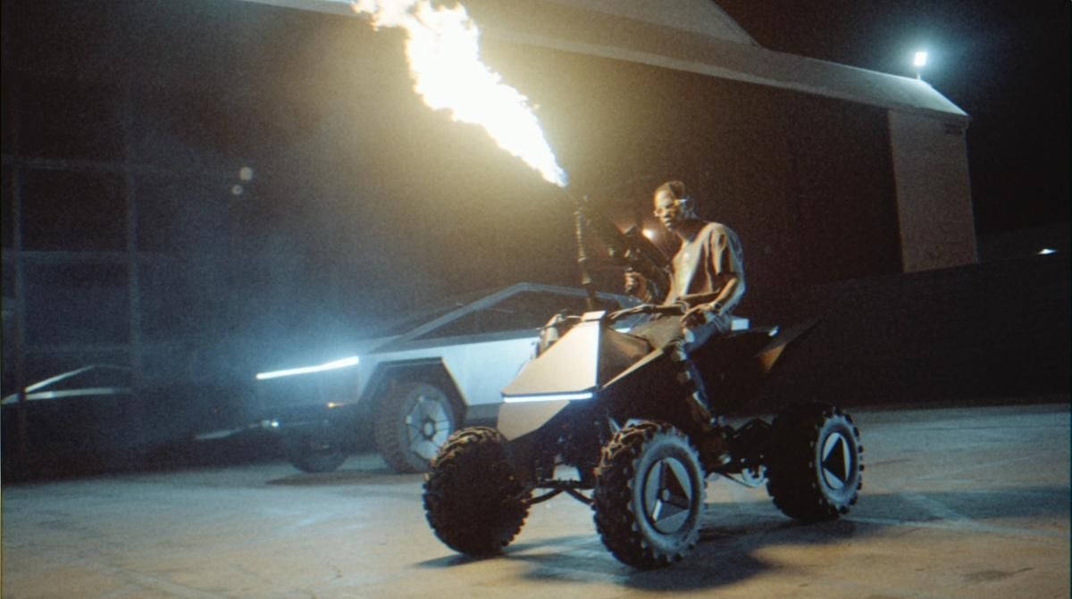 男子在夜間騎著噴火ATV，靠近未來主義汽車。