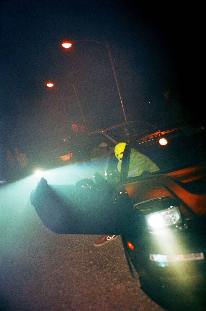 戴黃色頭盔的人夜晚從車門探身，車頭燈亮著。