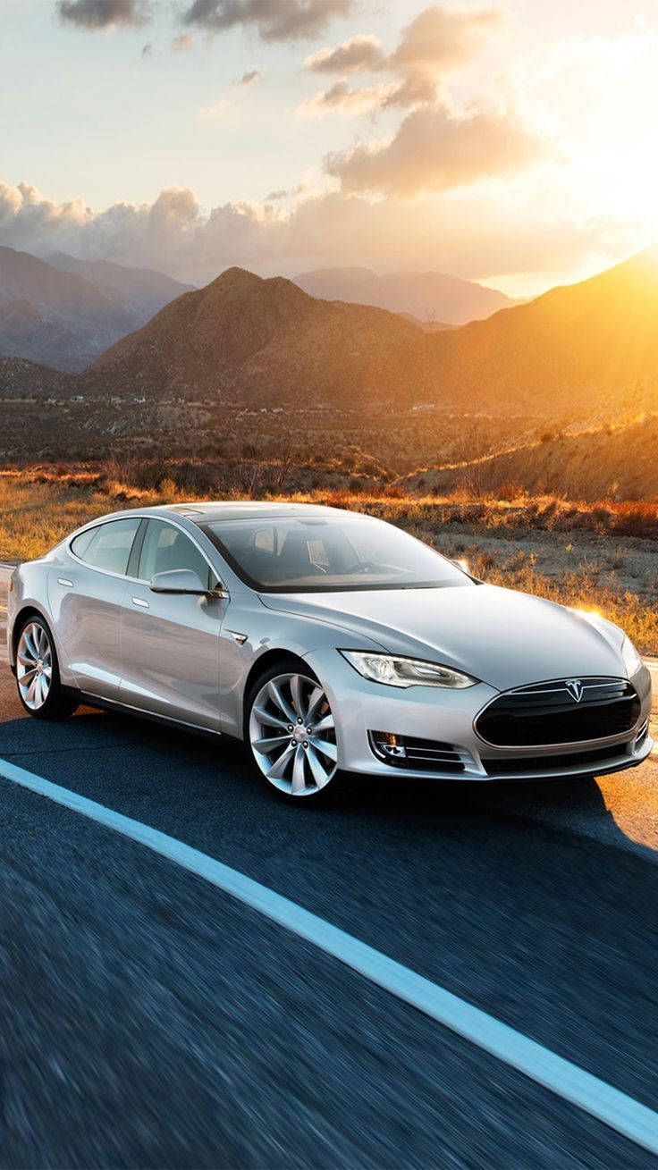 特斯拉Model S銀色版 壁紙 — 一輛銀色Tesla Model S在日落時分沿沙漠公路飛馳，背景是金色的山脈。