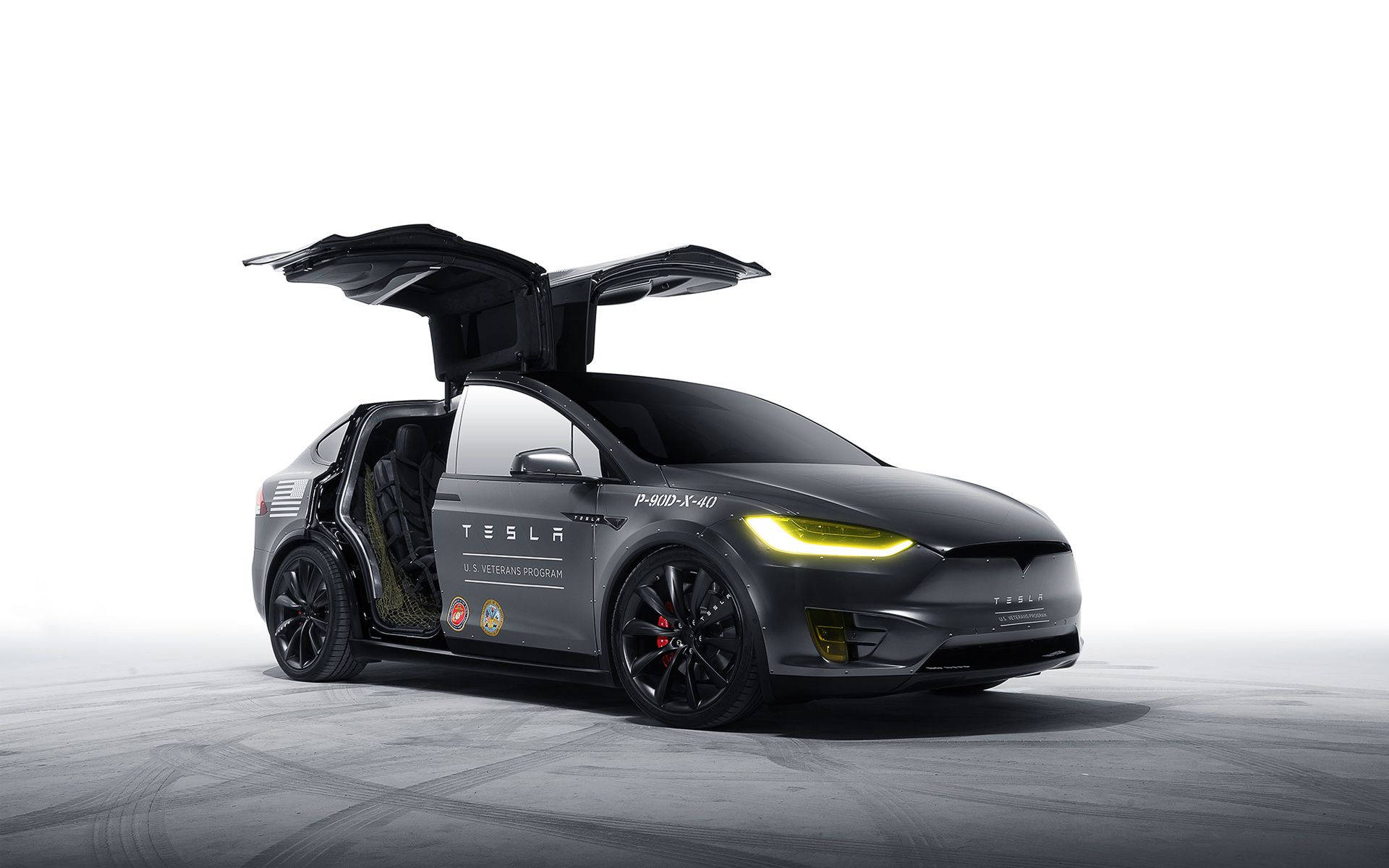 特斯拉Model X灰白色 壁紙 — 一輛時尚的黑色Tesla Model X，鷹翼門打開，車頭燈發光，並帶有美國退伍軍人計劃貼紙，位於簡約的攝影棚地板上。