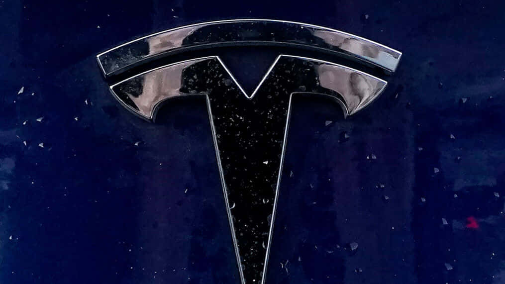 夜間濕引擎蓋上的鍍鉻 Tesla 標誌，帶有雨滴。
