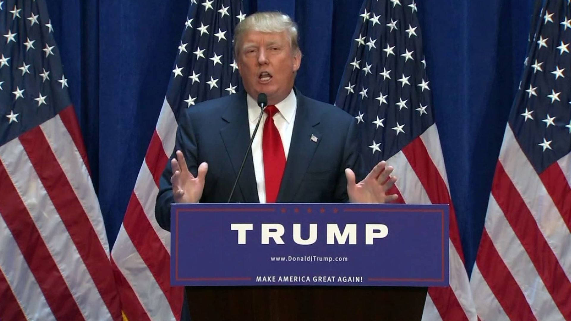 特朗普競選宣佈 壁紙 — 當勞·特朗普在講台上熱情演講，'TRUMP'和'MAKE AMERICA GREAT AGAIN'文字兩旁有美國國旗。