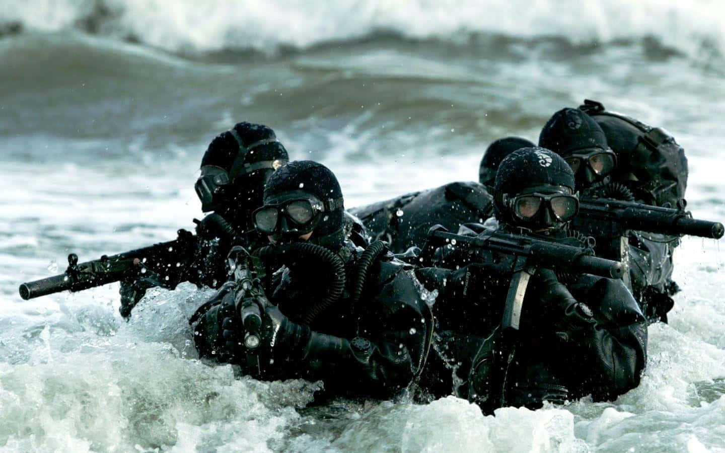 身穿戰術裝備的士兵在洶湧的海浪中涉水前進，手持步槍。