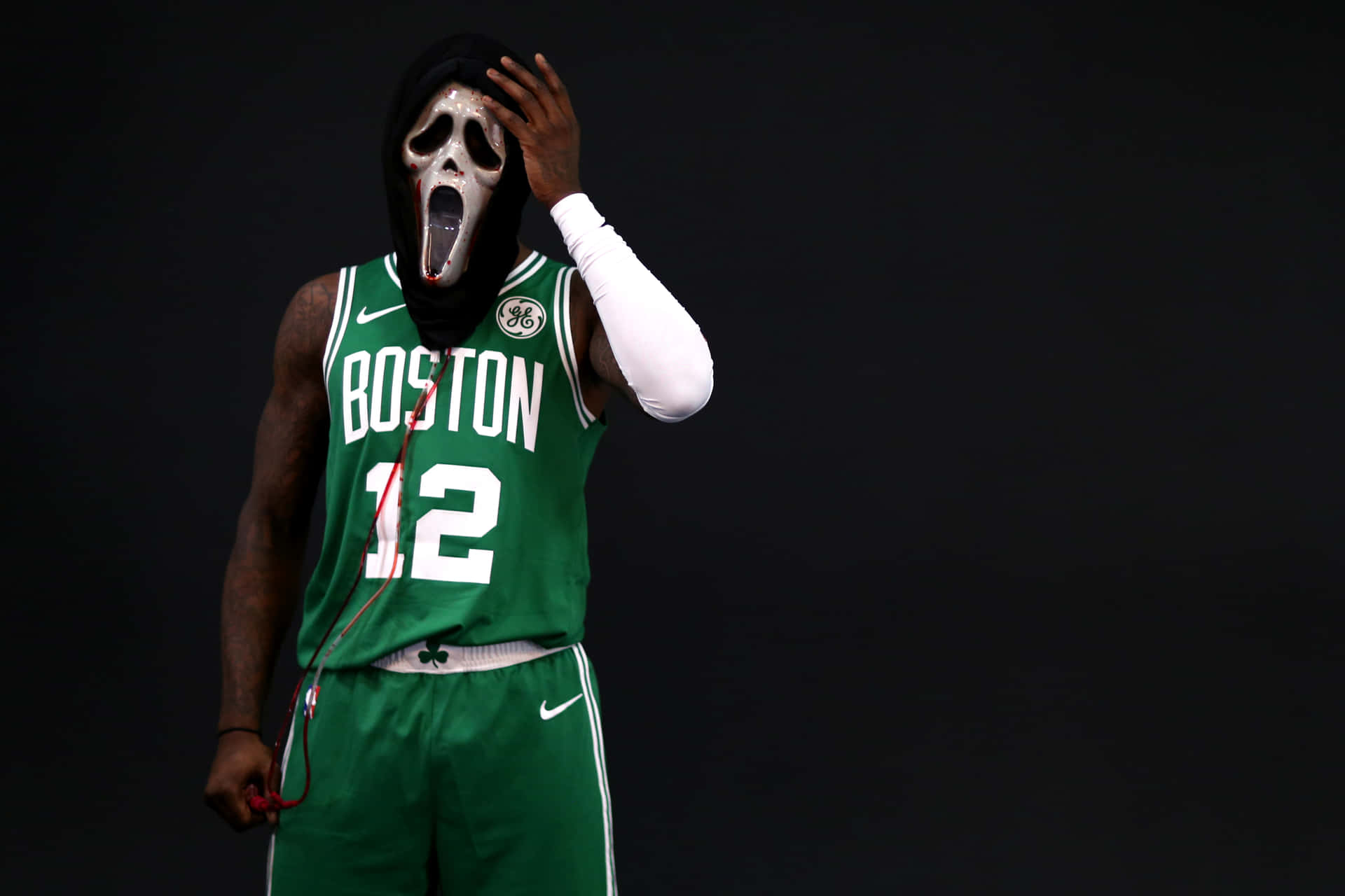 身穿綠色波士頓球衣的籃球運動員戴著Ghostface面具托著頭。