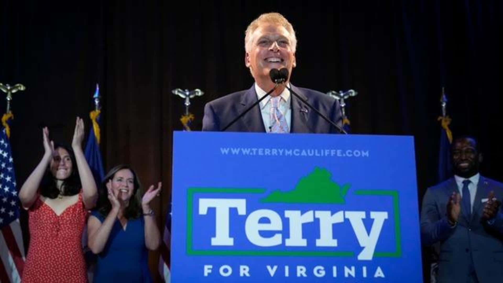 Terry McAuliffe 在維珍尼亞州的競選活動中，與歡呼的支持者和美國國旗一起。