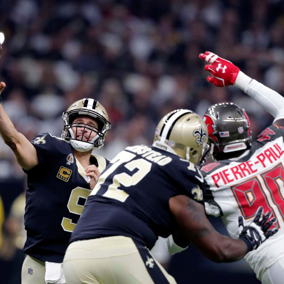 特龍·阿姆斯特德 Offensive Tackle 保護四分衛 壁紙 — 新奧爾良聖徒隊的四分衛在坦帕灣海盜隊防守端鋒皮埃爾·保羅的壓力下，在座無虛席的體育場中傳球。